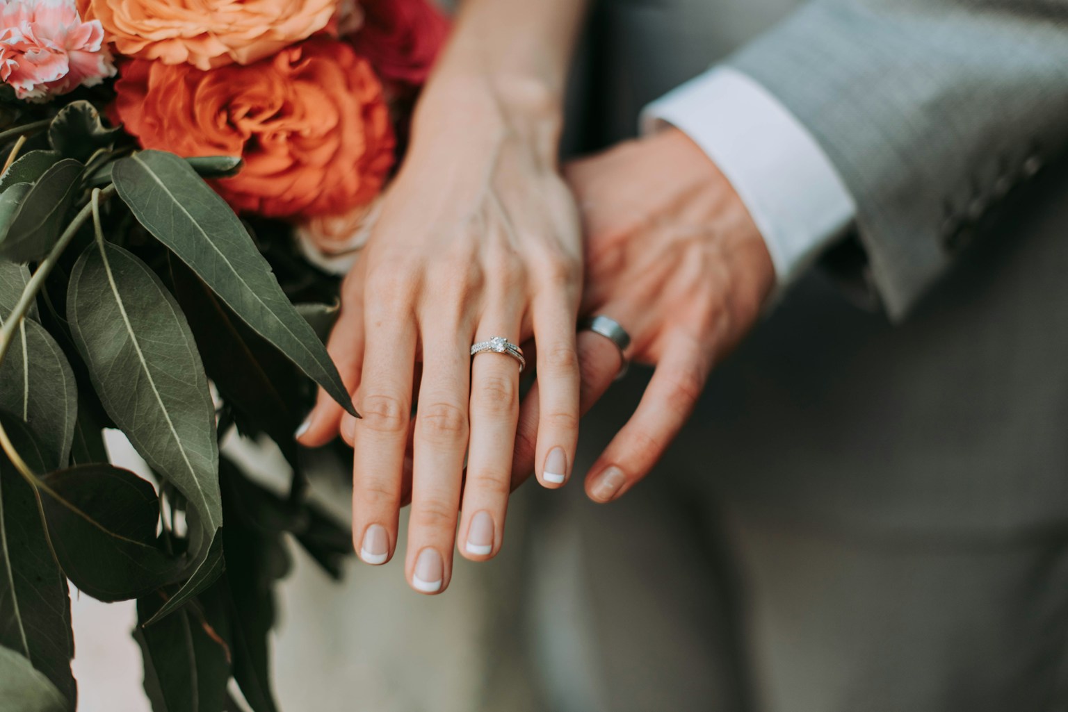 Couple placing their hands together beside wedding flowers