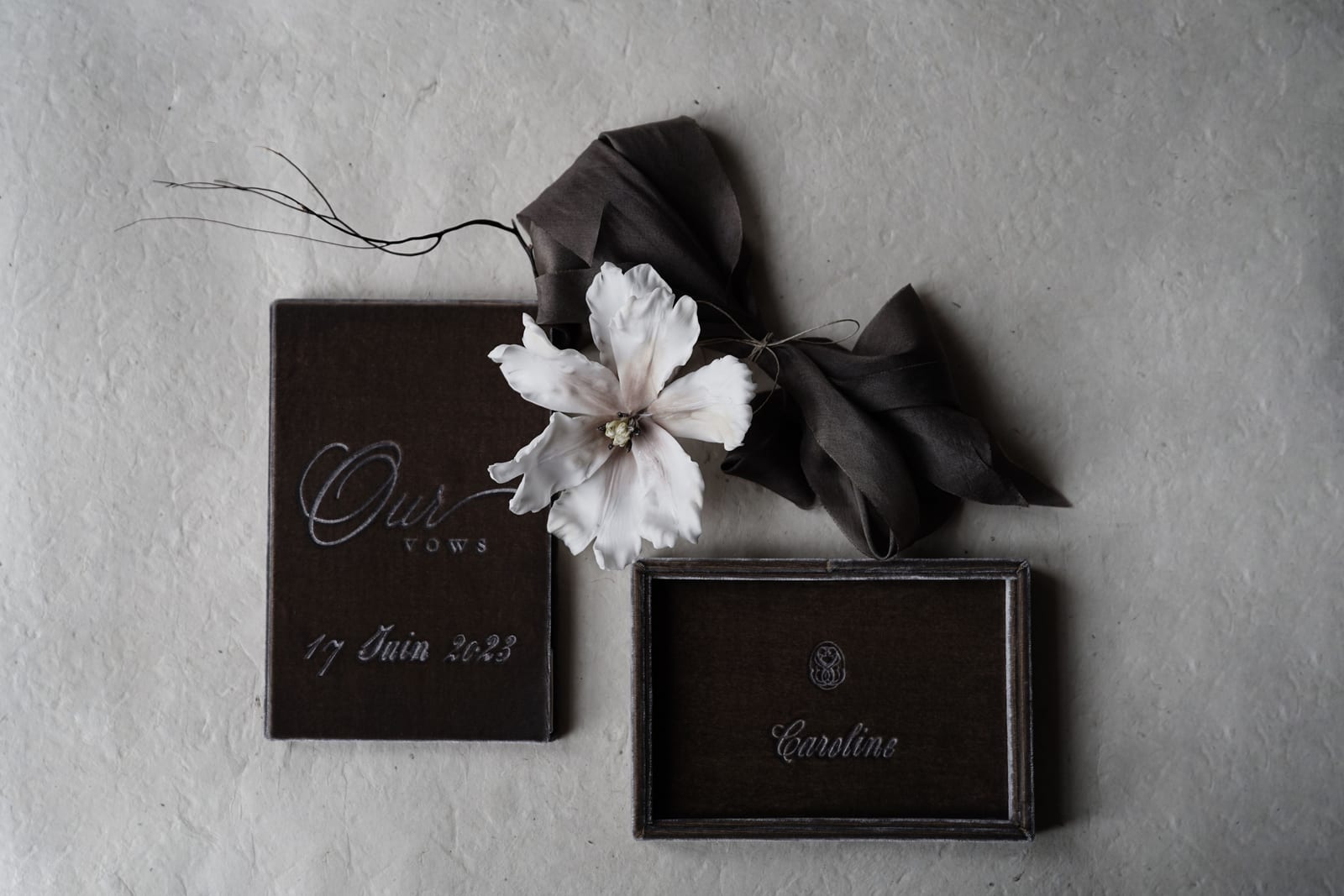 Wedding vow booklet tied with a ribbon beside a white flower