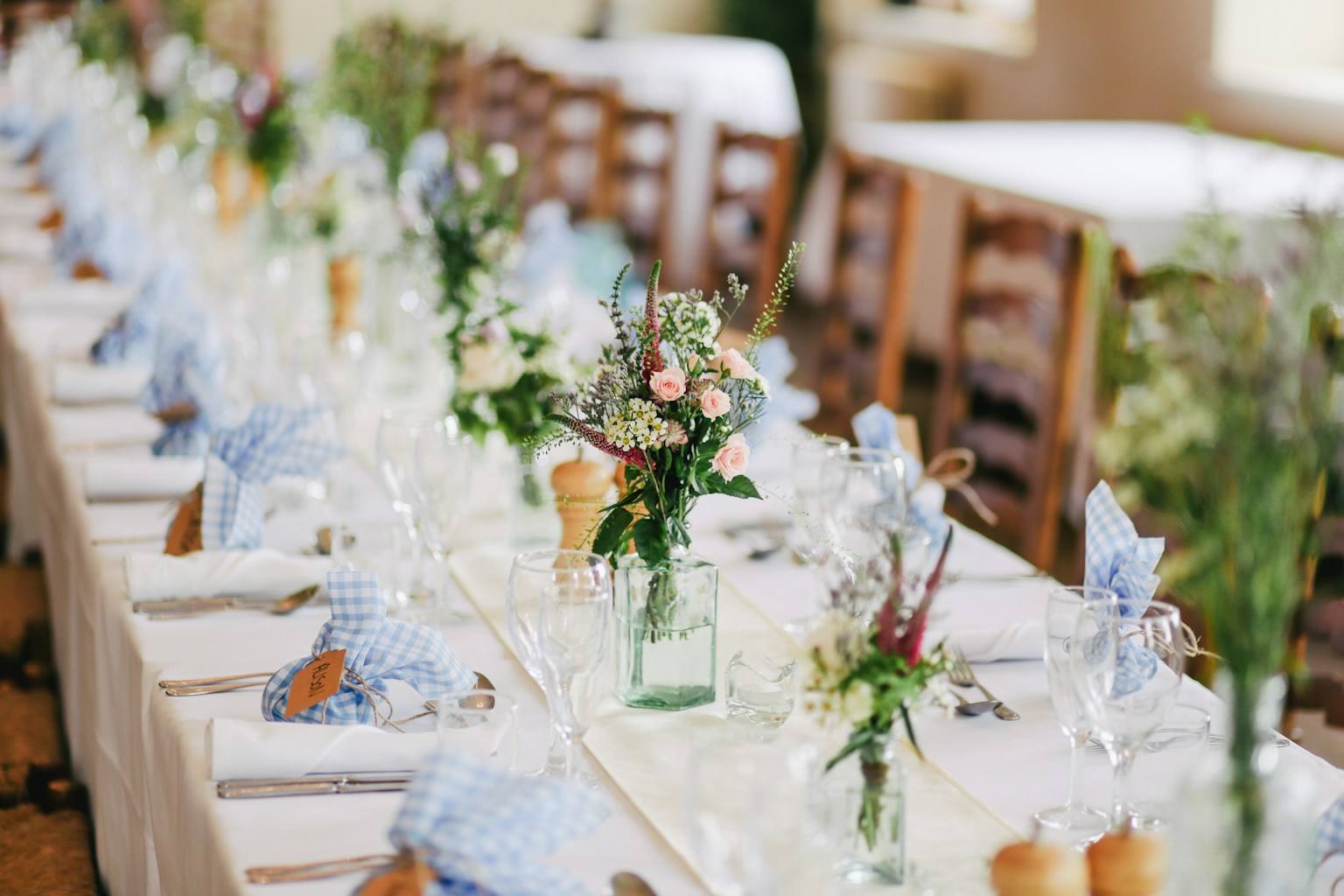 Wedding flowers and place settings arranged on a long table