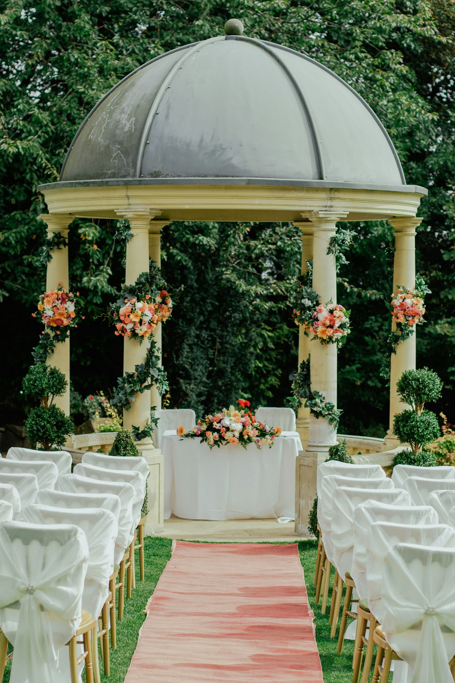 Garden ceremony space with a floral arch and empty chairs
