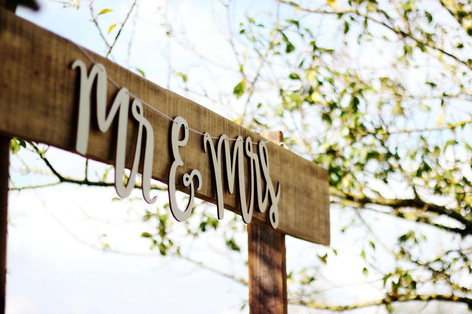 Wooden Mr and Mrs sign hanging from a garden arbor