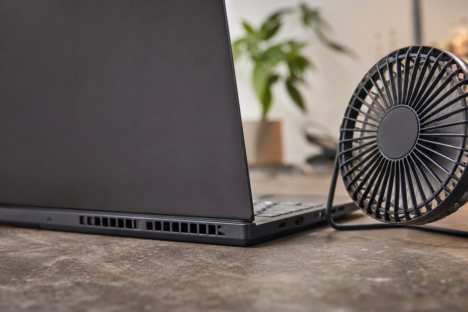 Laptop vents kept clear beside a small desk fan