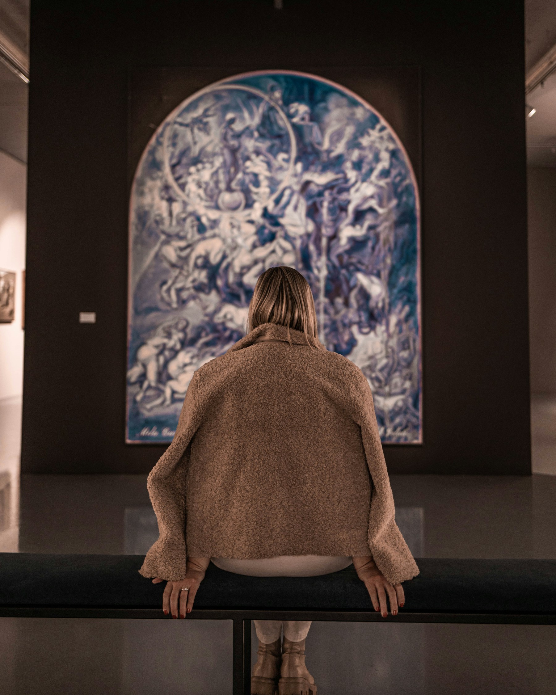 A woman quietly looking at an abstract painting in a gallery