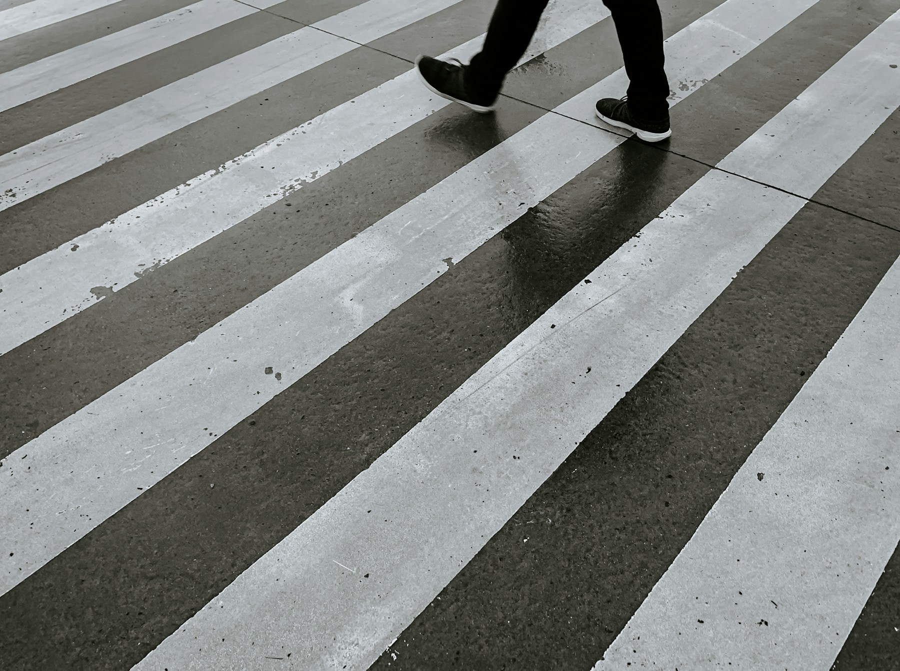 A person walking across a striped city crosswalk