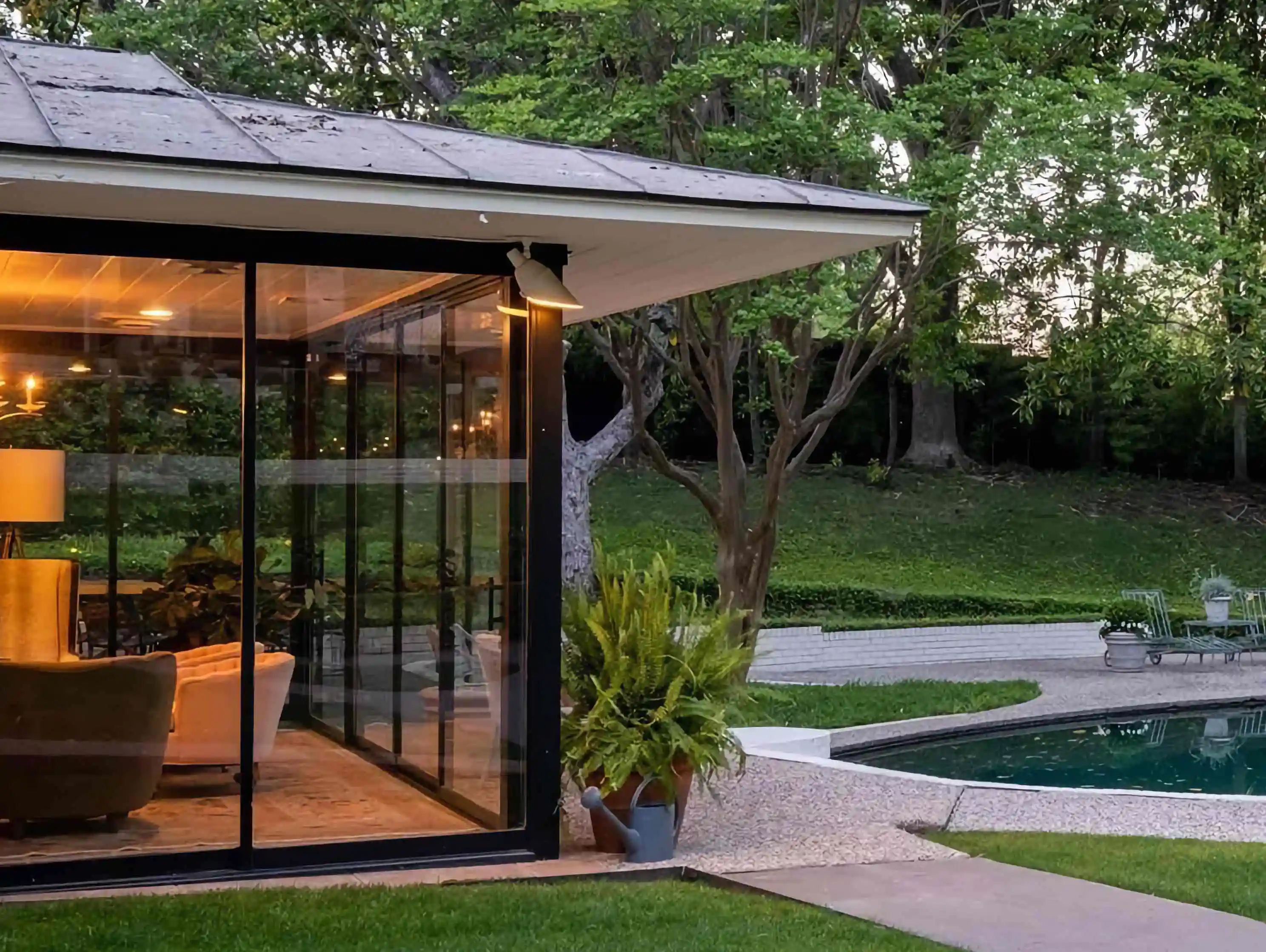 the backyard of a home with a glass room and pool