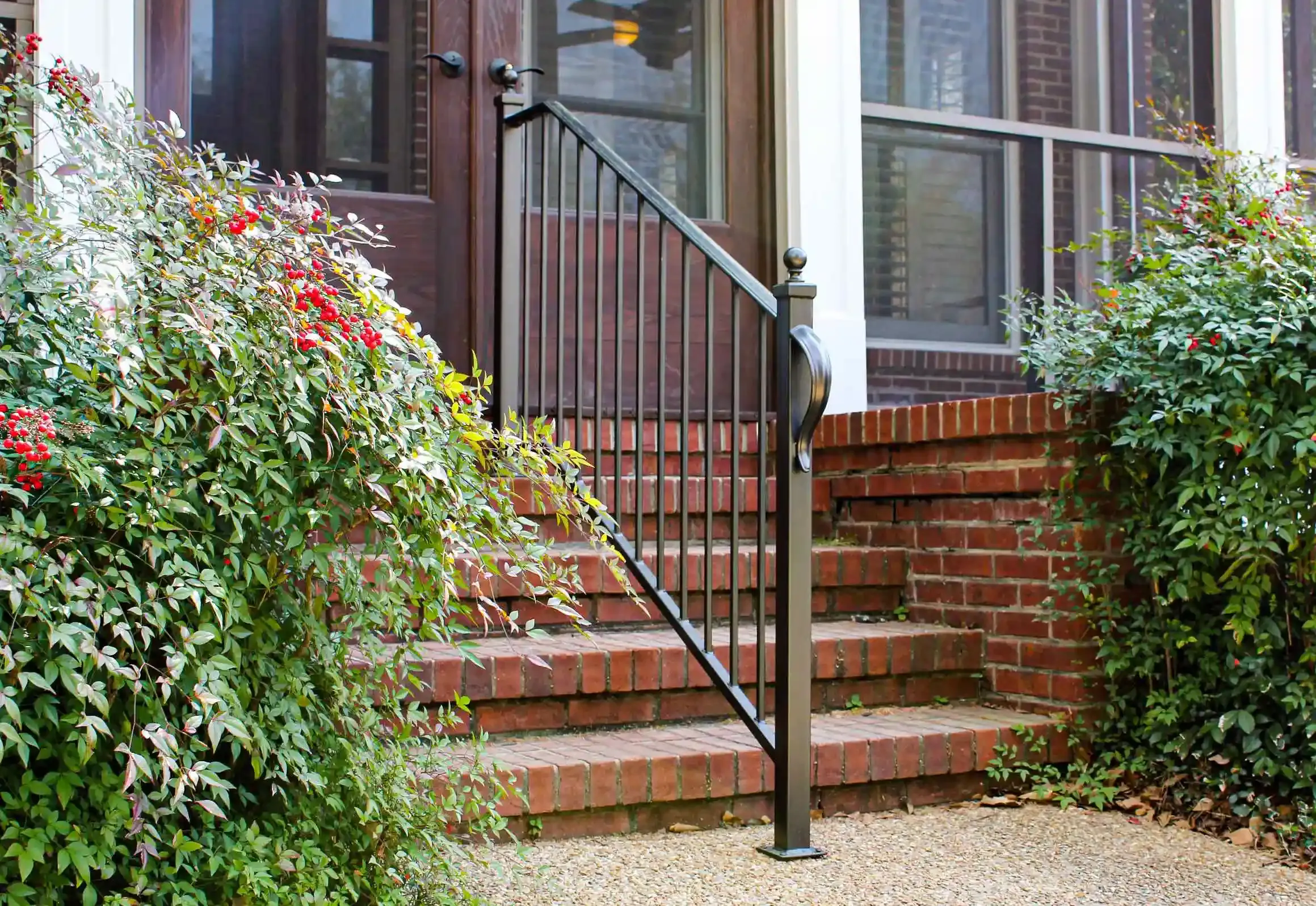 a black iron railing going up the center of red brick stairs leading to the front of stairs