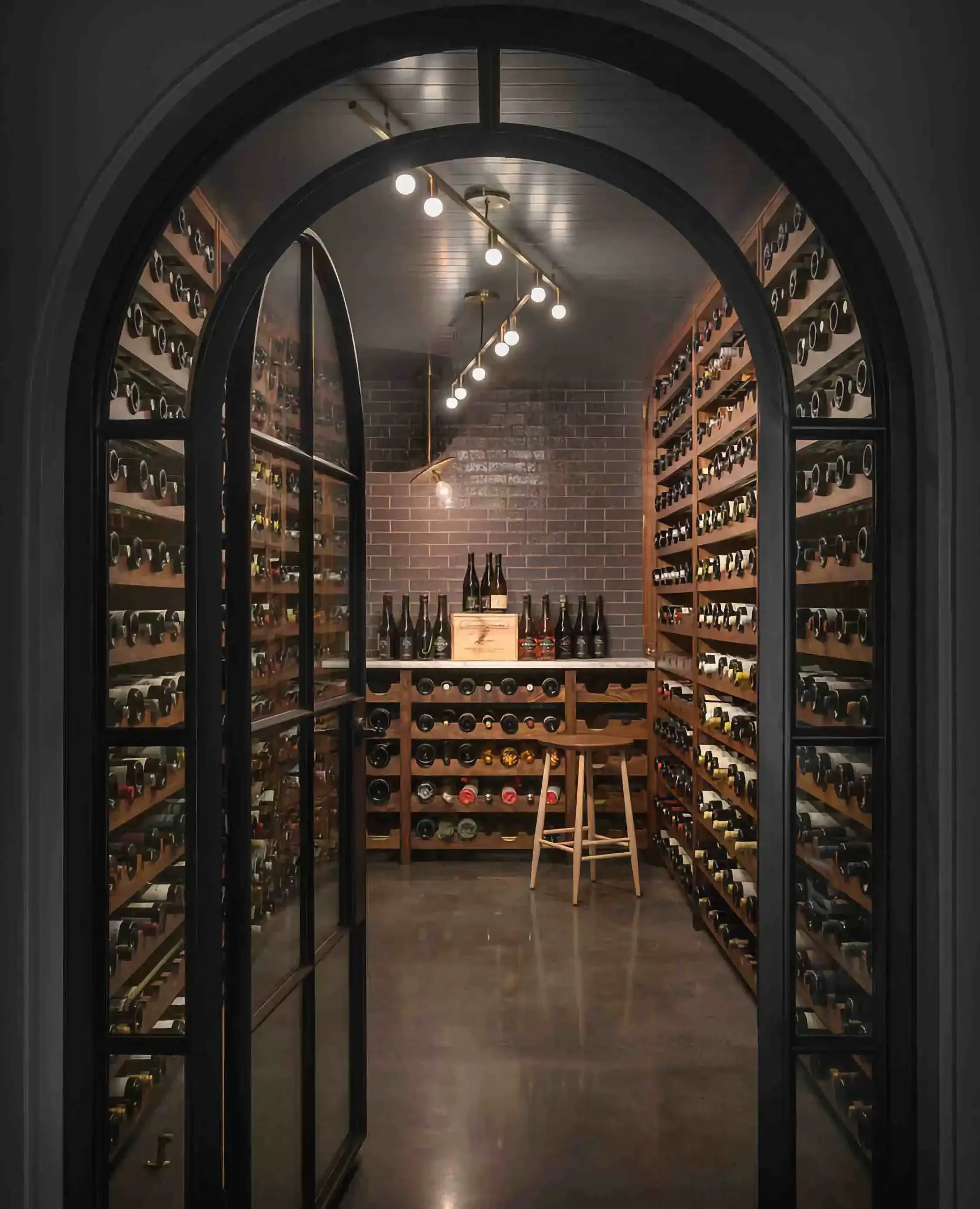 an outside view of a wine cellar behind a large arched black iron and glass door opened
