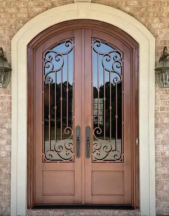 an iron double door made to look like dark wood with large panes of glass on each door with intricate black iron lines on each; the doors are arched at the top into a half circle