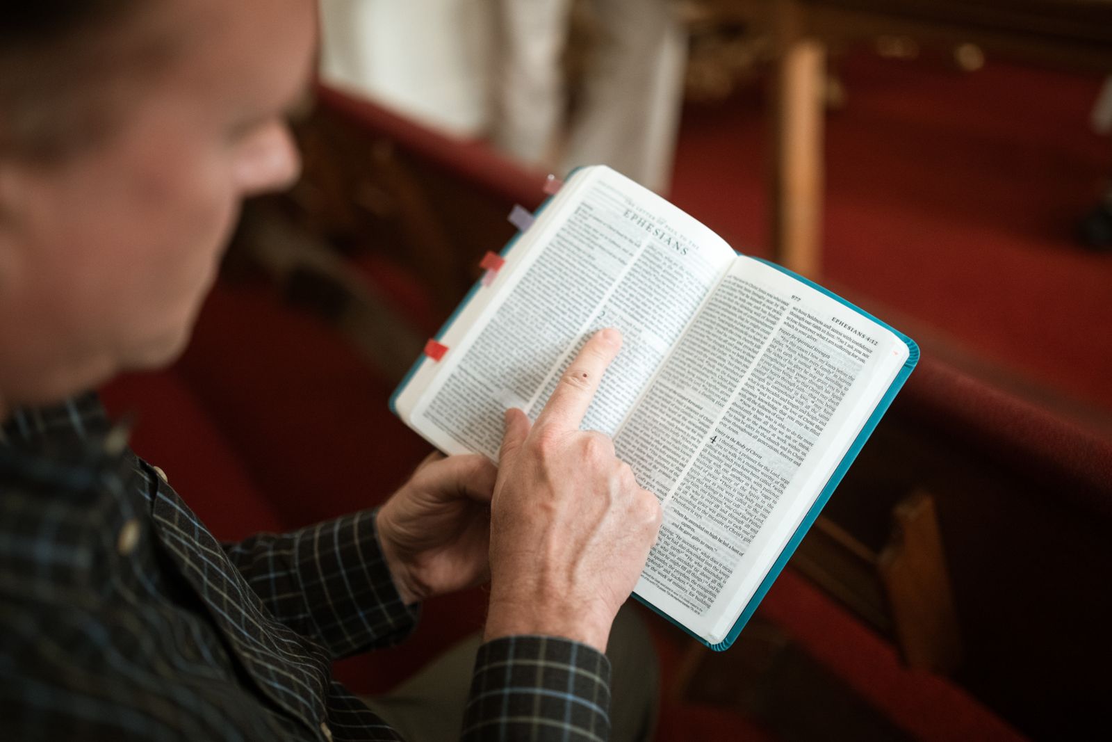 Persona leyendo la Biblia con atención en una banca de iglesia