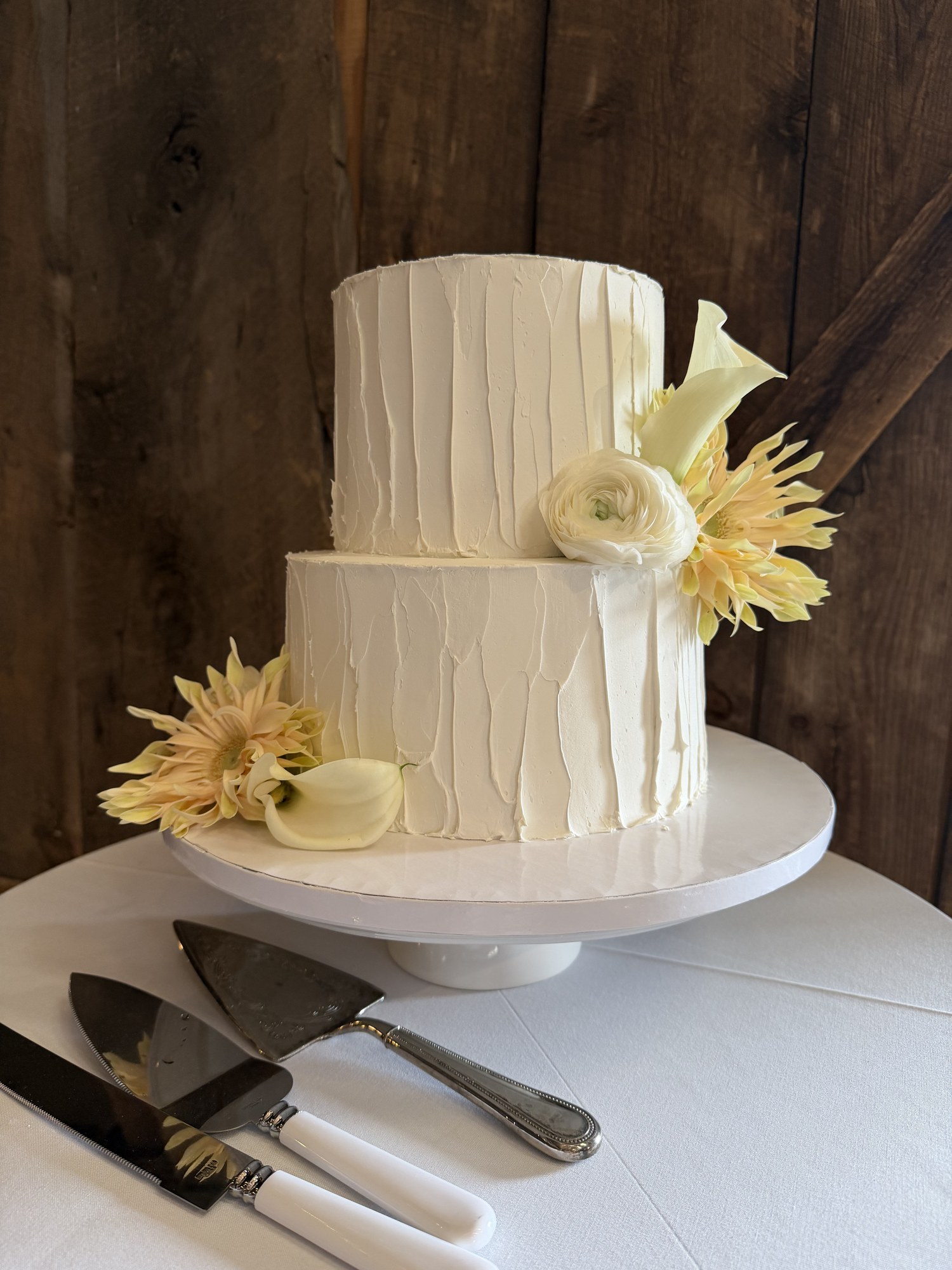 Two-tier ivory wedding cake with textured buttercream and pale yellow flowers
