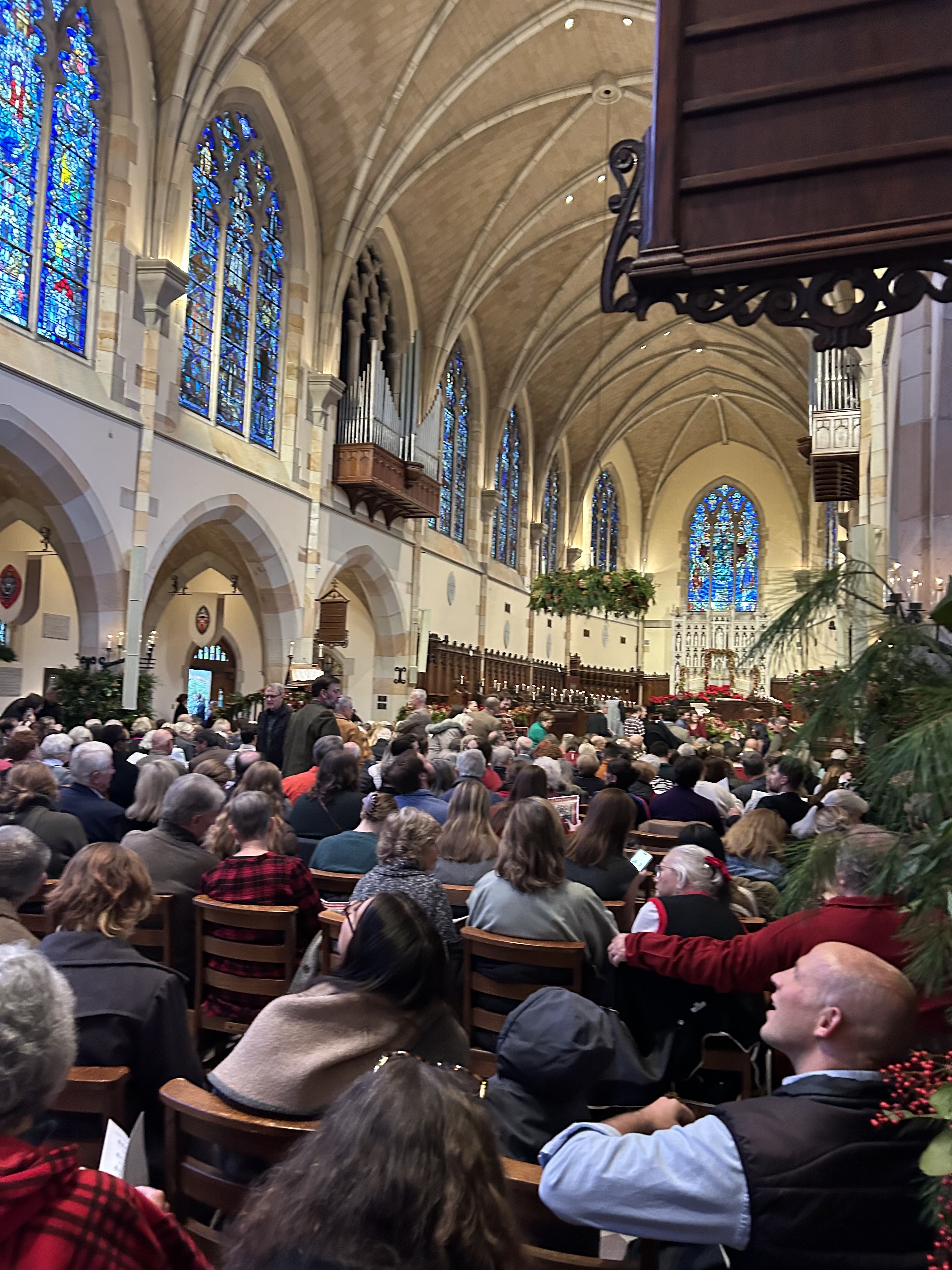Community gathering inside a stone chapel with stained glass windows