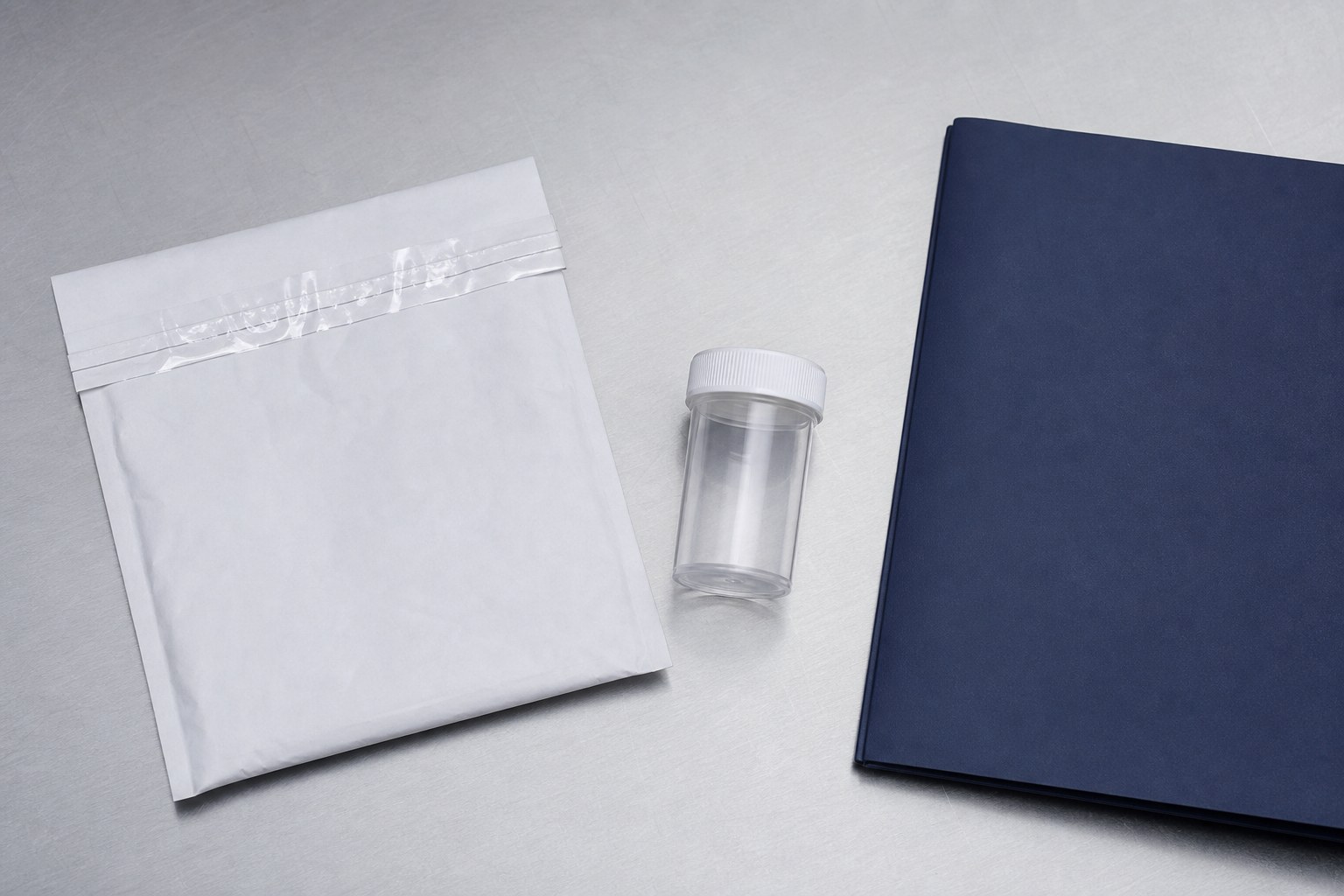 Sealed sample envelope, clear storage vial, and closed navy folder arranged on a clean work surface