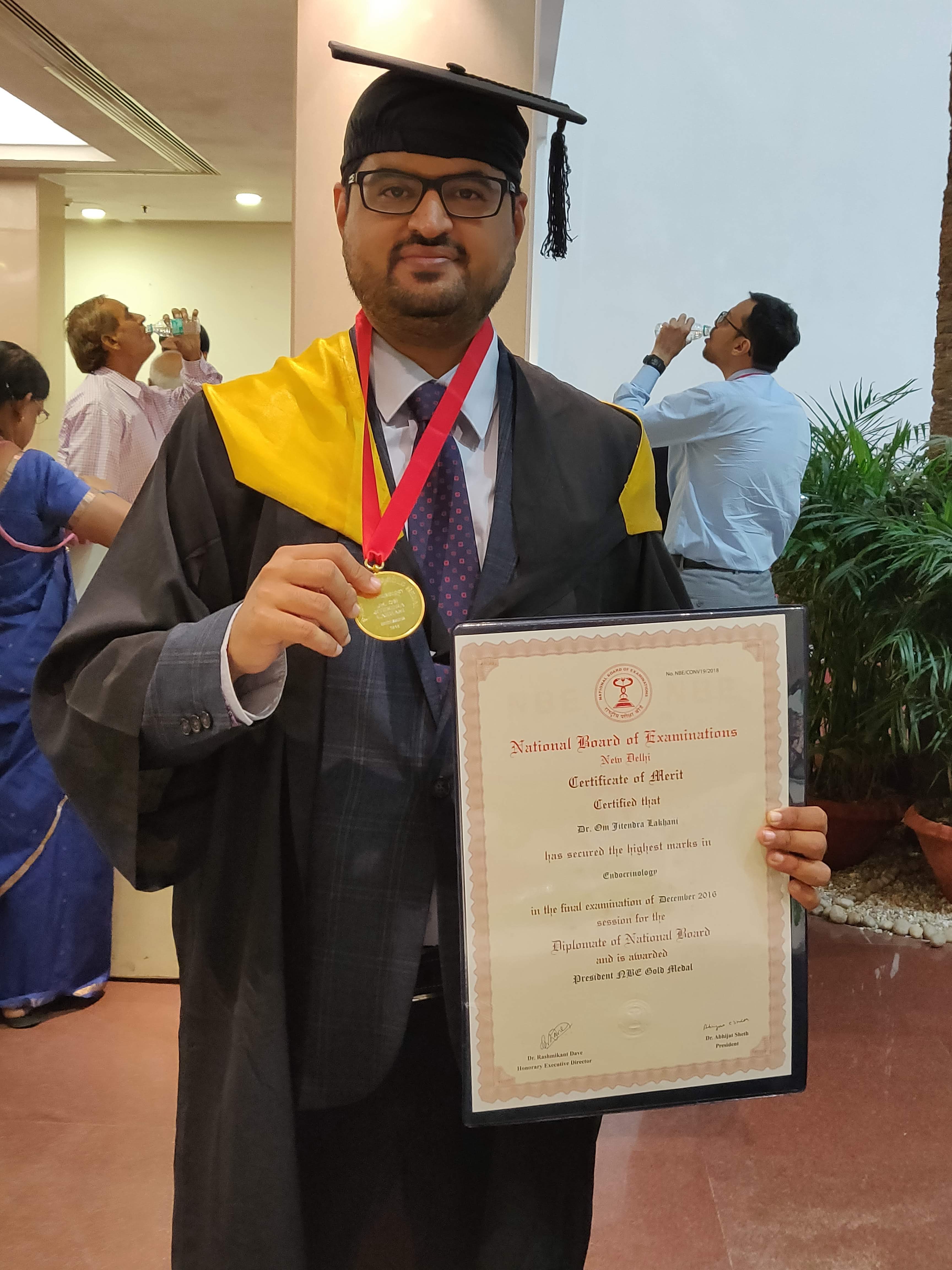 Dr. Om J Lakhani holding a medal and certificate at a graduation ceremony