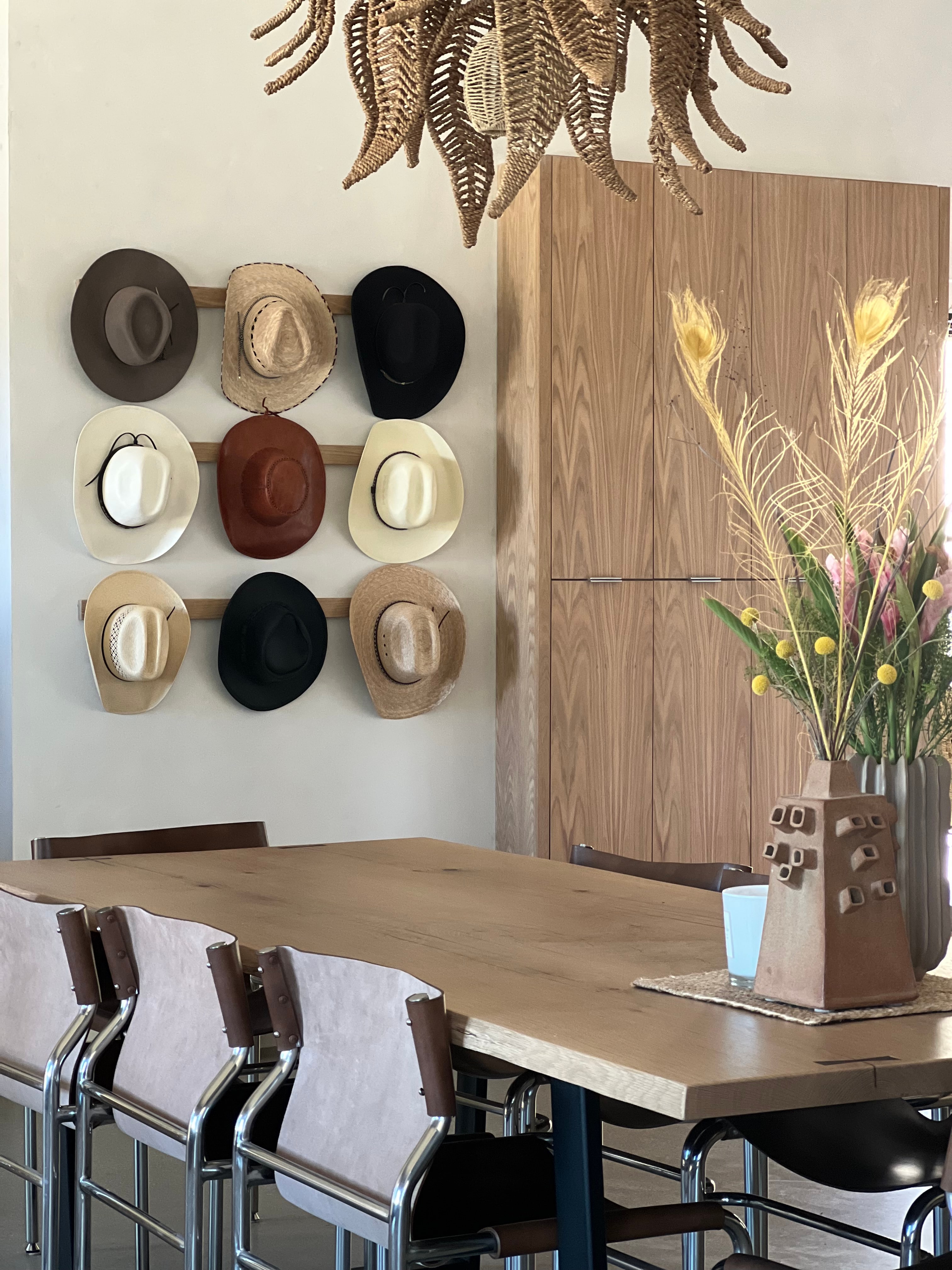 Layered dining room with a graphic hat wall, sculptural lighting, and tailored seating
