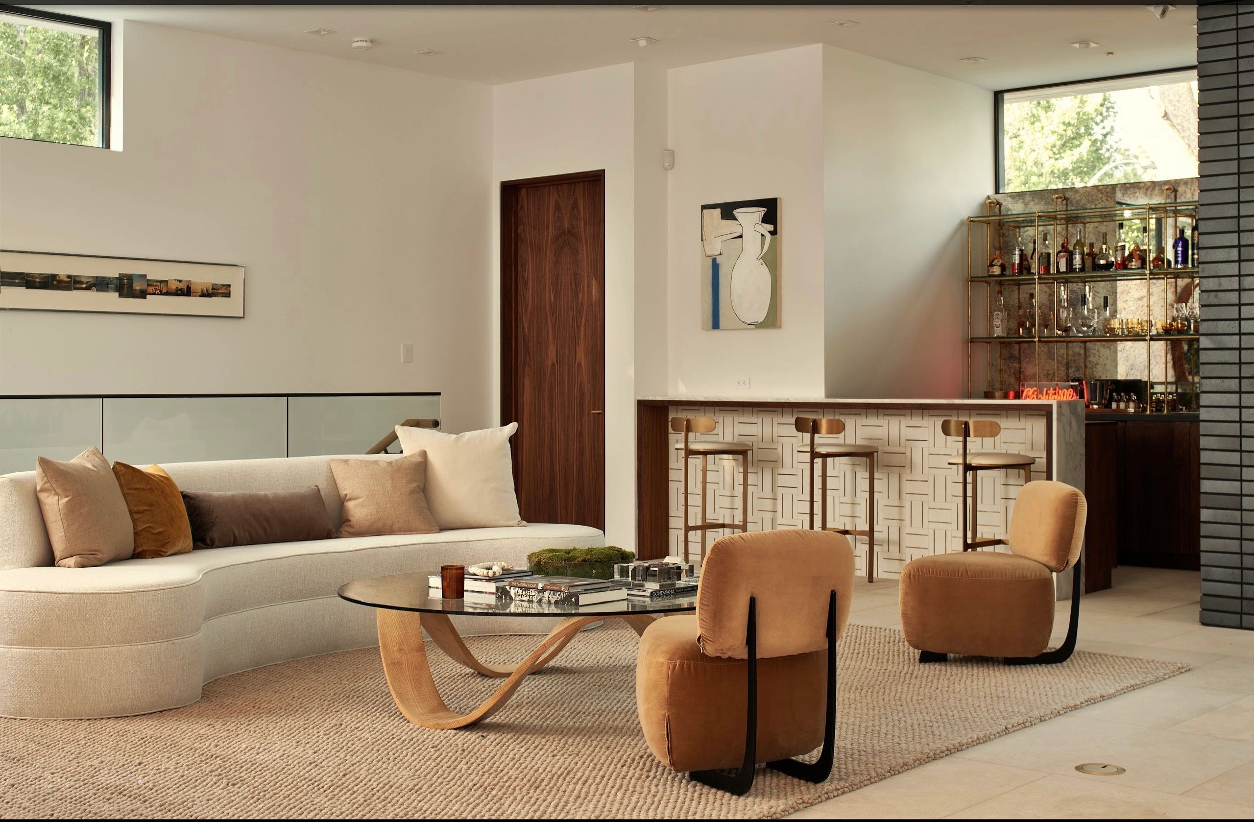 Warm modern residential interior with art, seating, and a bar