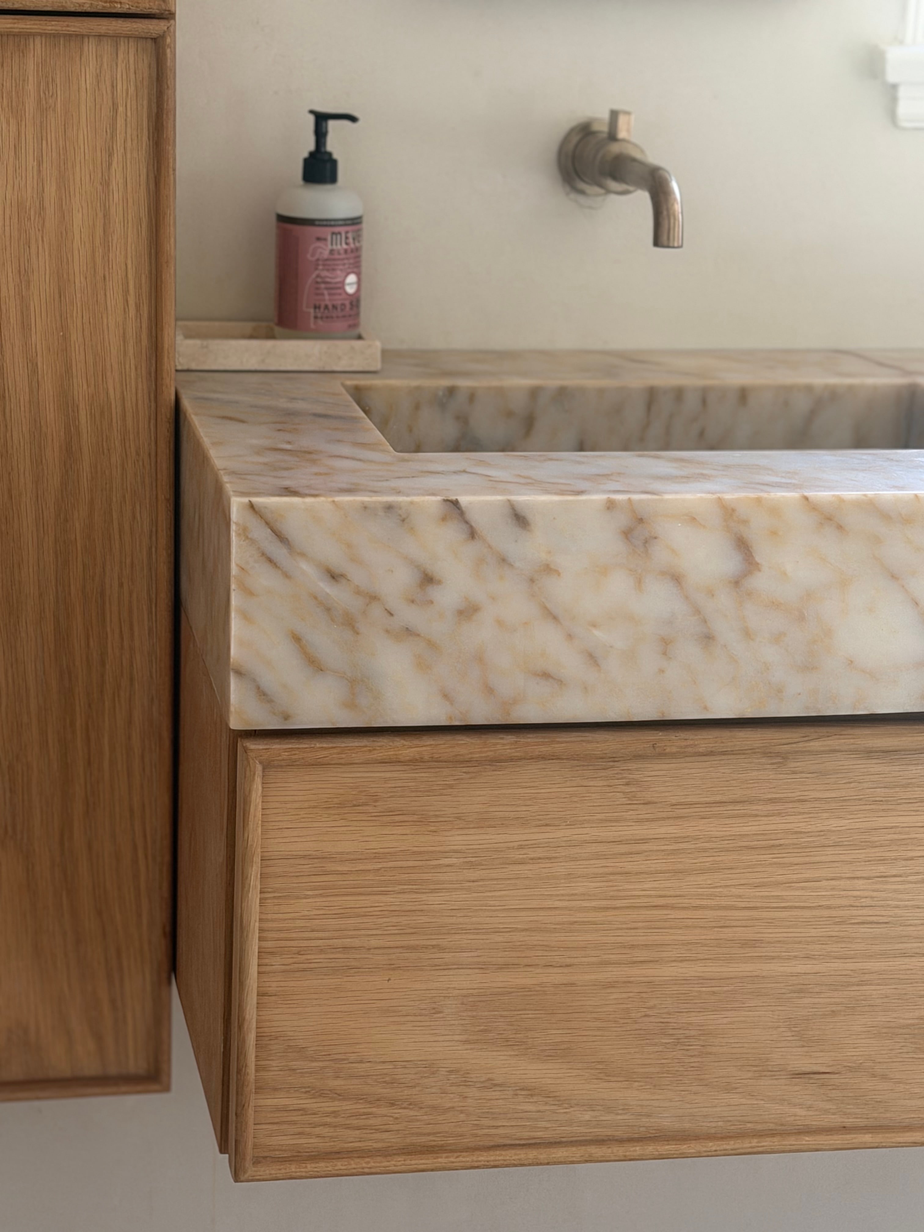 Close-up of custom Calacatta Macchia Vecchia marble double vanity and floating timber cabinetry