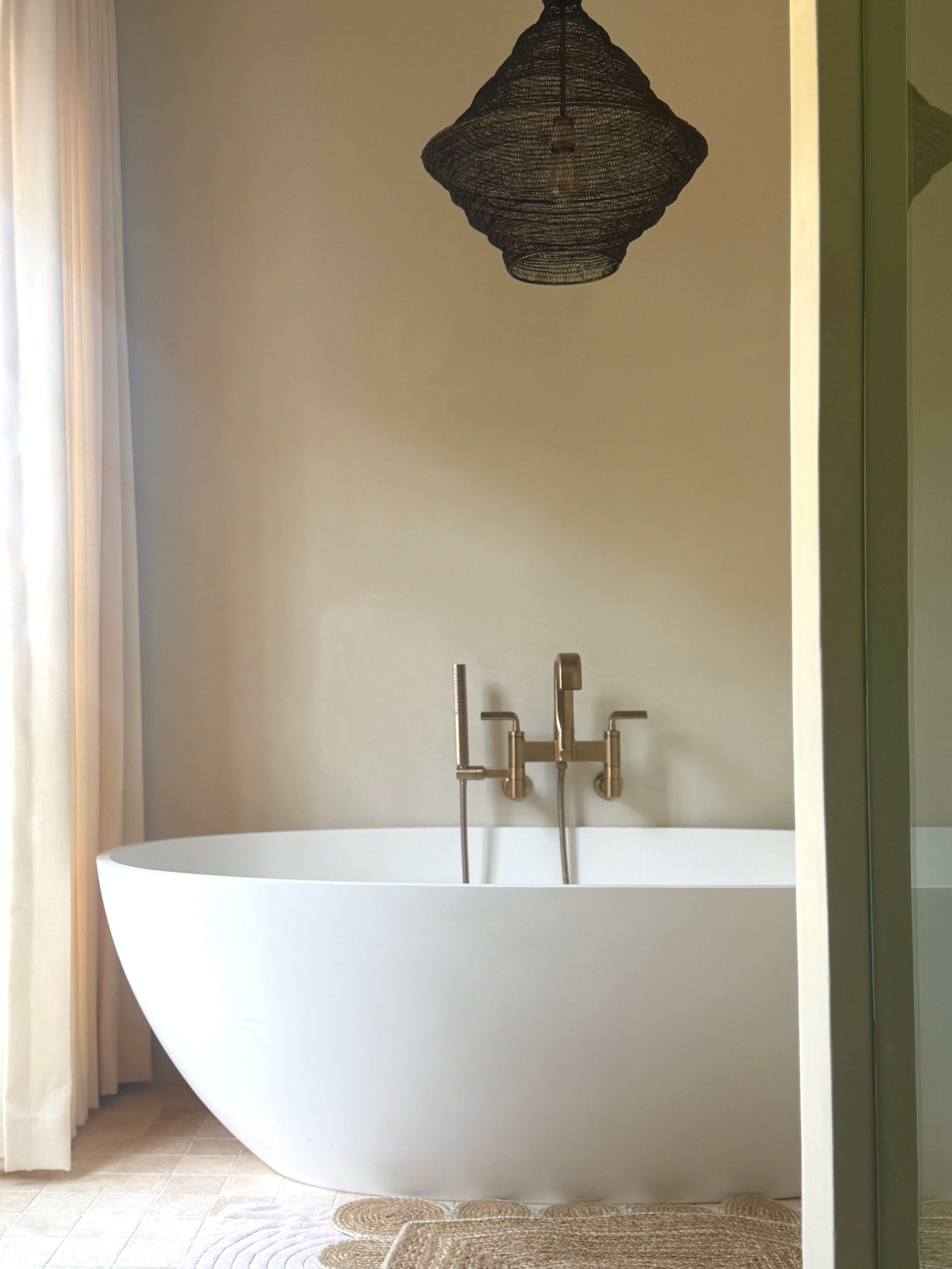 Freestanding bath with wall-mounted fittings and woven pendant in the Hollywood Hills Residence primary bathroom