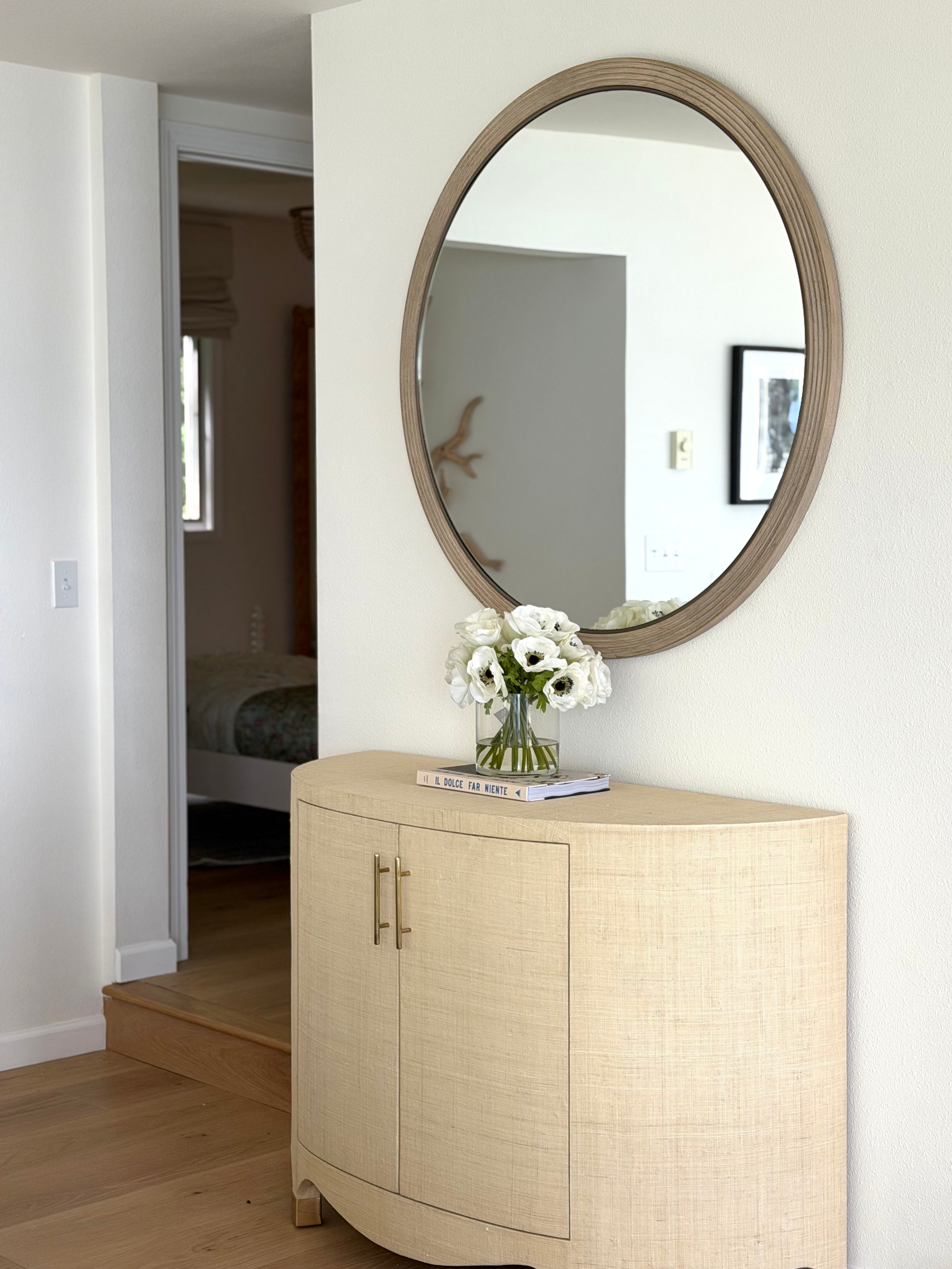 Idaho Lakeside Retreat entry detail with a round mirror, textured cabinet, and white flowers