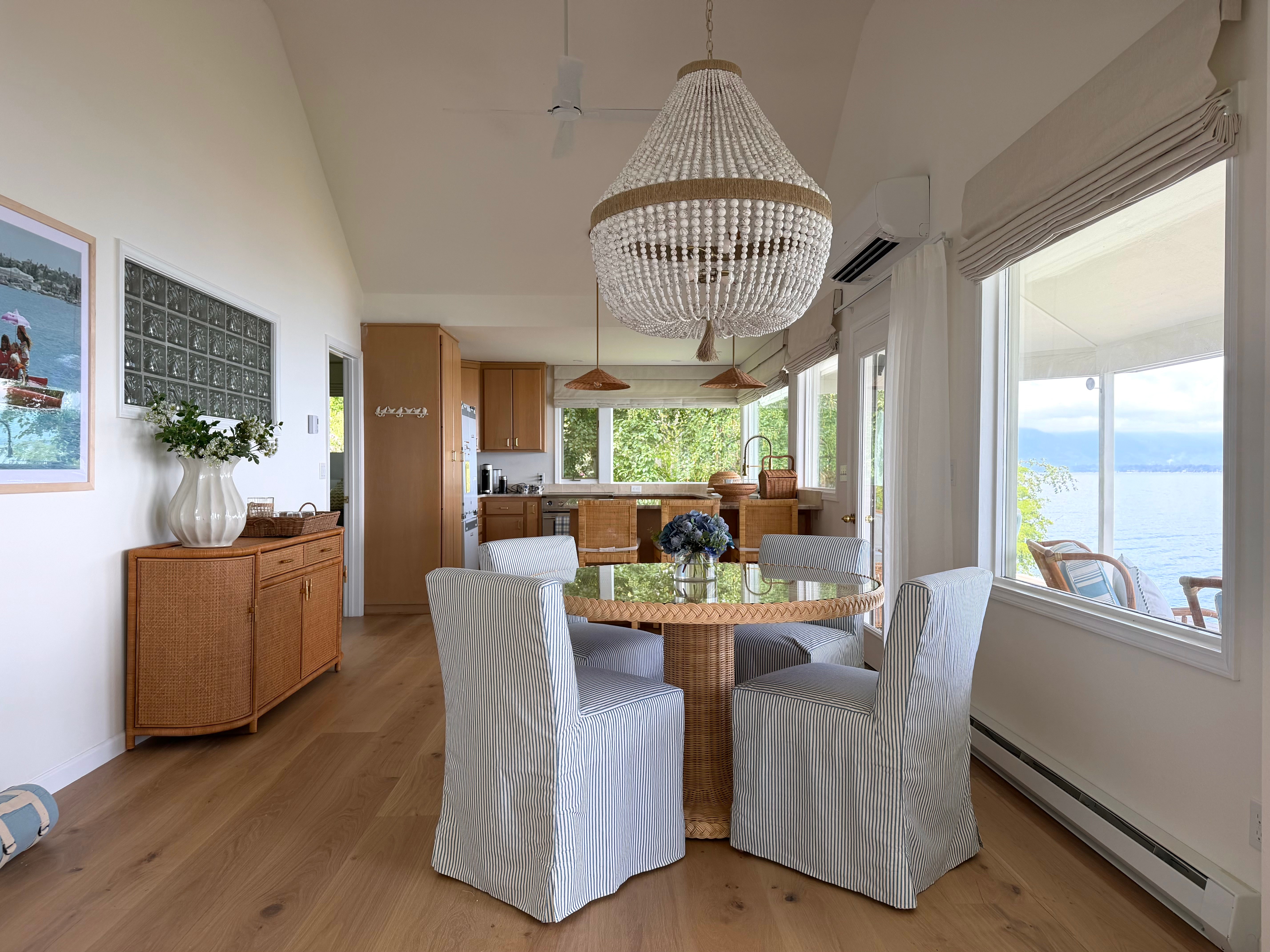 Idaho Lakeside Retreat dining area with striped chairs, woven rattan furniture, and a beaded chandelier overlooking the water