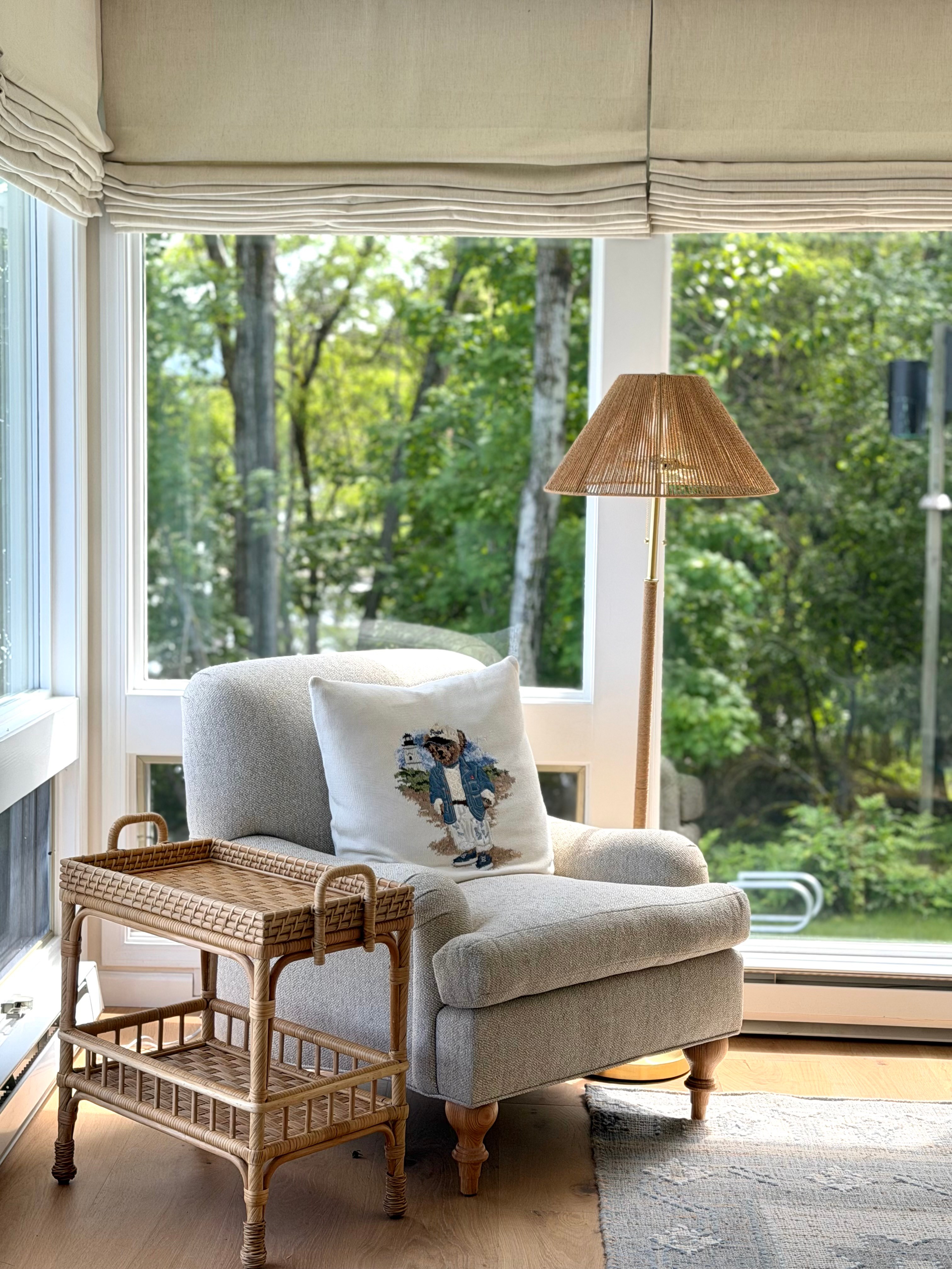 Idaho Lakeside Retreat reading nook with a textured armchair, woven rattan table, and woodland view