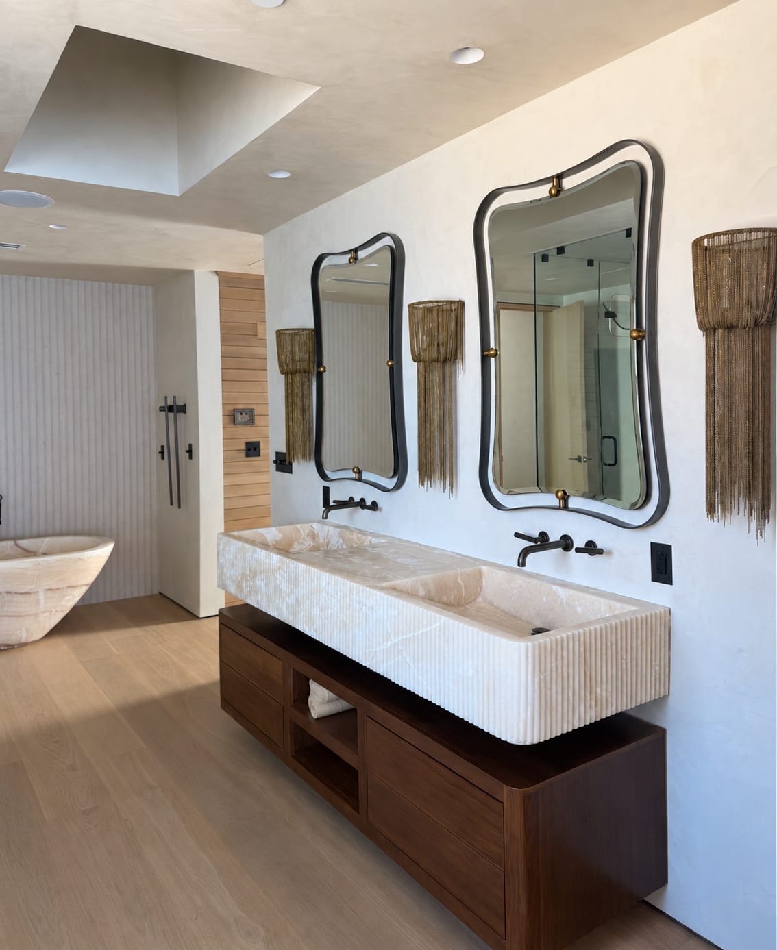 Tailored double vanity with reeded stone, onyx basins, and warm walnut cabinetry