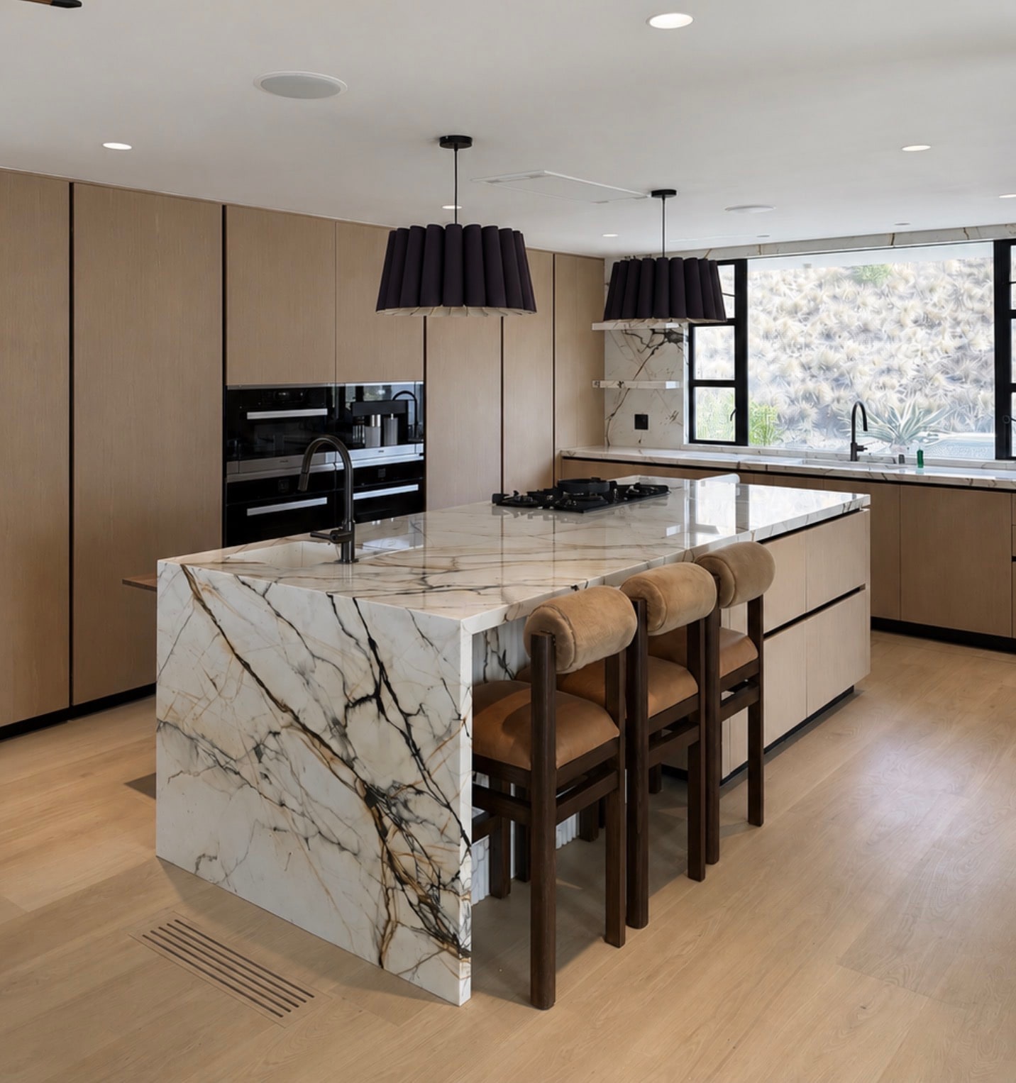 Natural oak kitchen cabinetry, dramatic veined stone island, black pendant shades, and wood counter stools
