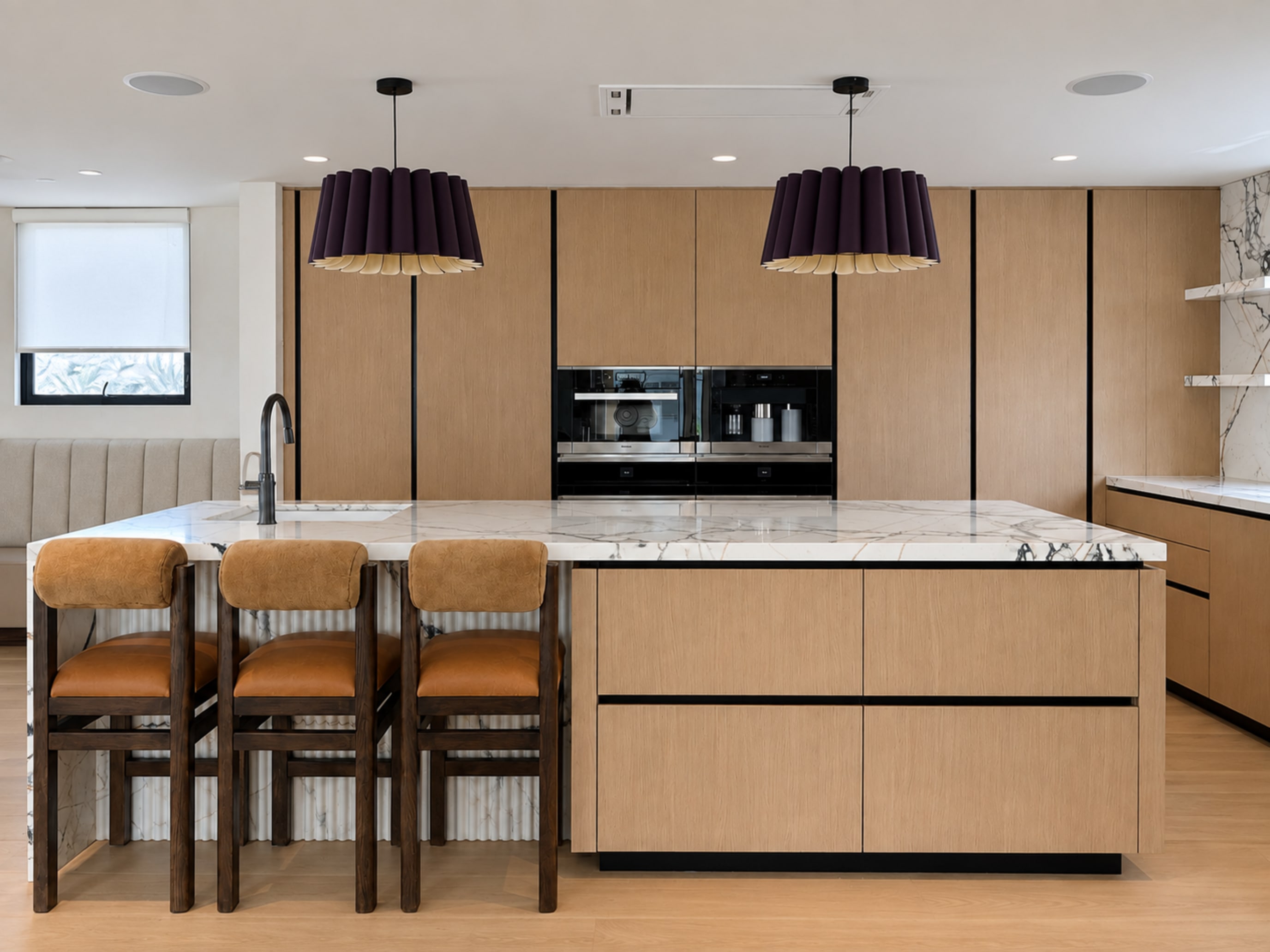 Malibu Residence kitchen with oak cabinetry, stone island, and sculptural pendant lights