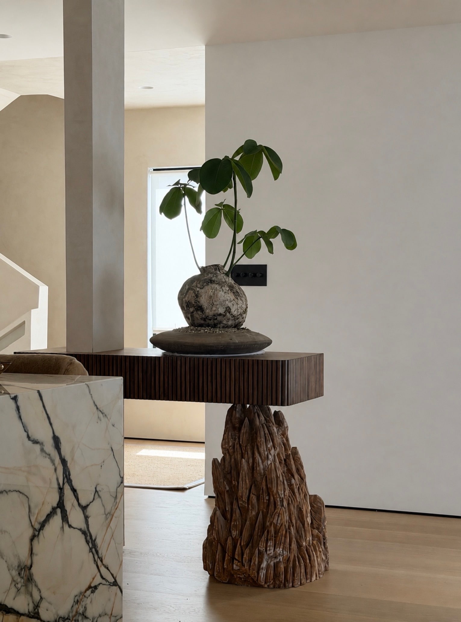 Malibu Residence interior with sculptural console, stonework, and botanical arrangement