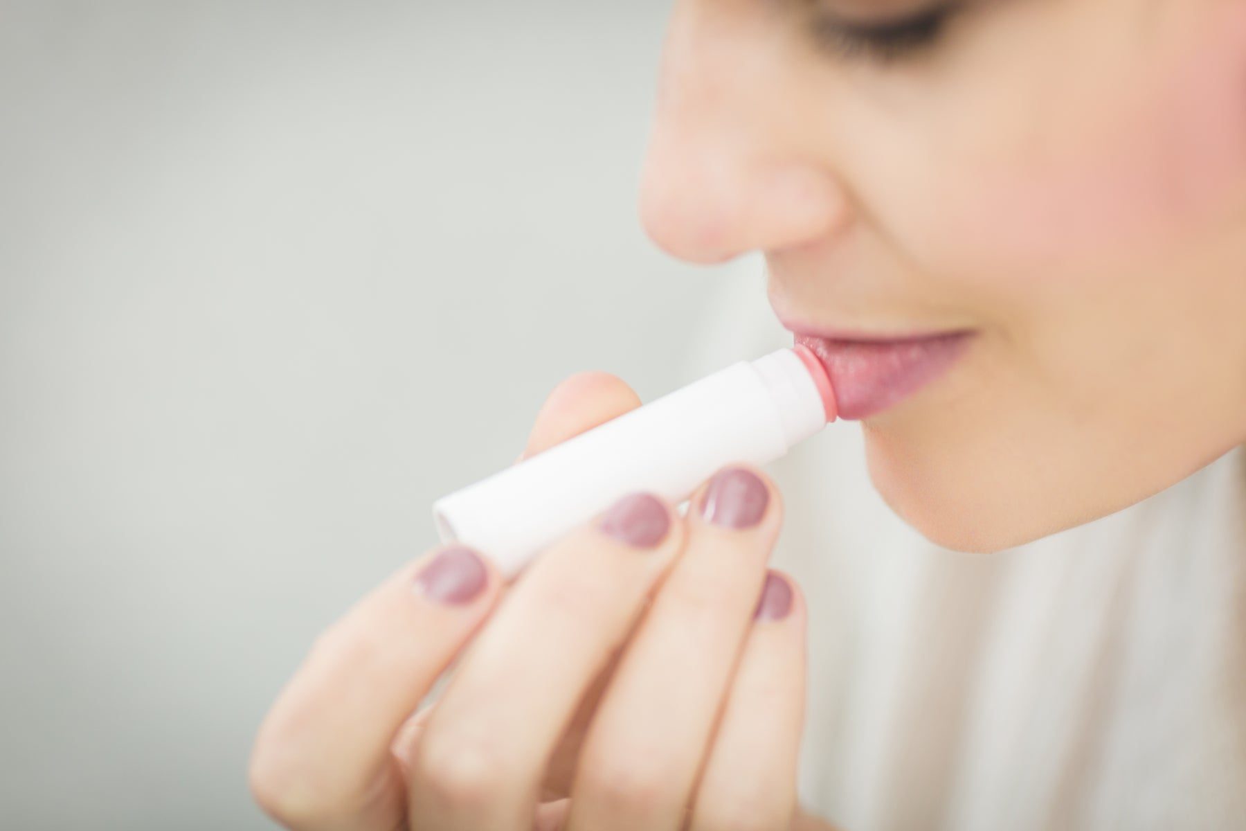 A close-up of a beauty routine with lip balm