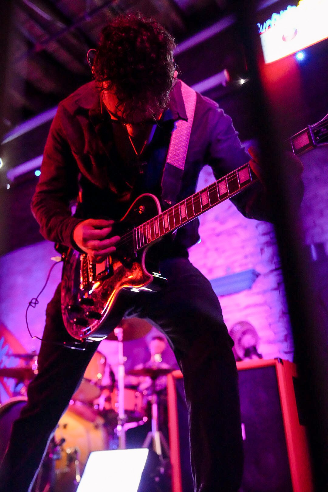 Guitarist leaning into a solo under purple stage lights