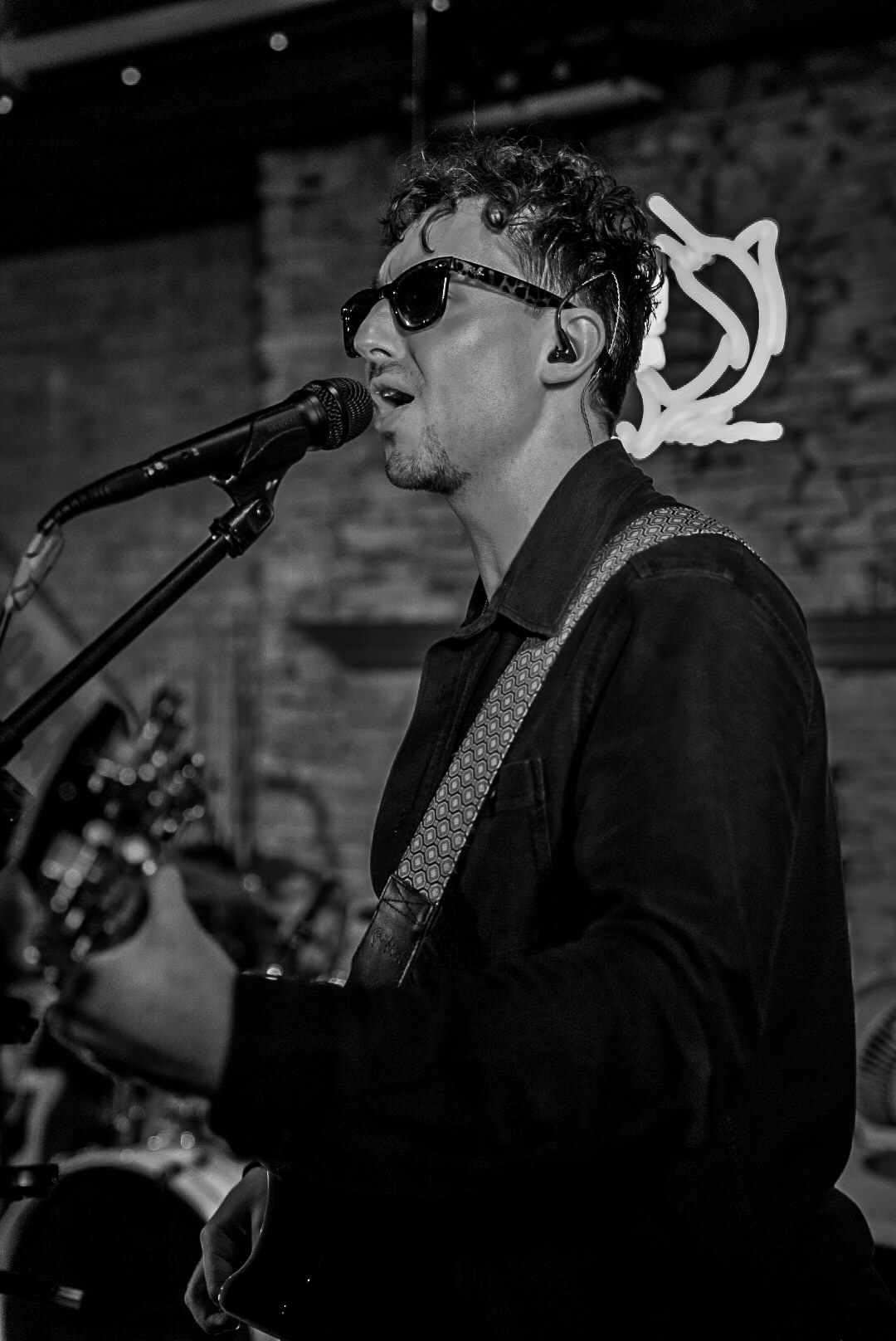 Guitarist singing into a microphone in black and white