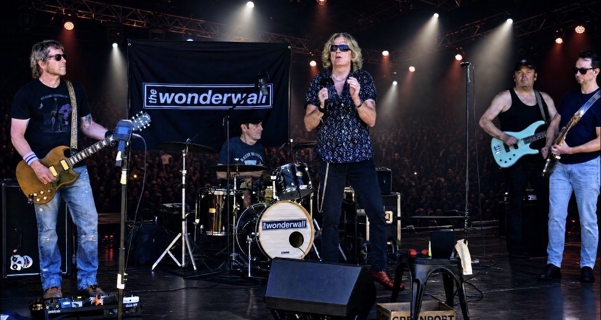 All five members of The Wonderwall performing live on stage