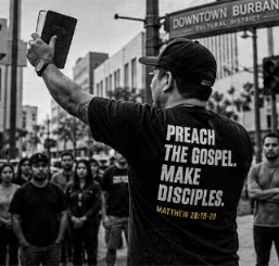 An evangelist holding up a Bible while preaching to a crowd in Burbank