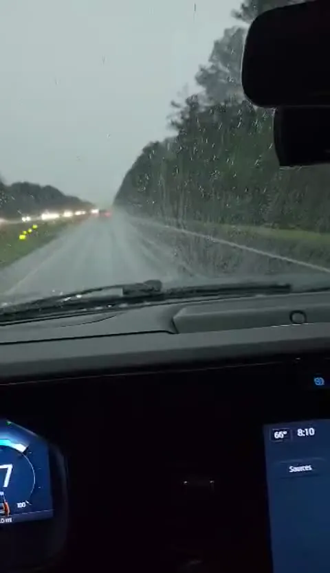 Rain falling on a windshield during a road drive