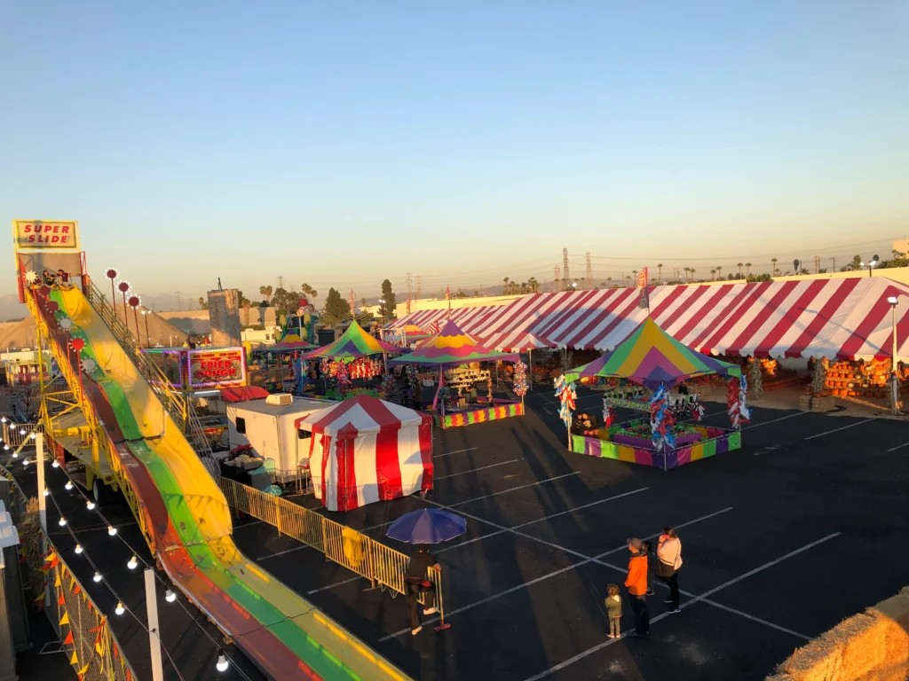 Rides, striped tents, and families at the Taghavi Farms Commerce pumpkin patch