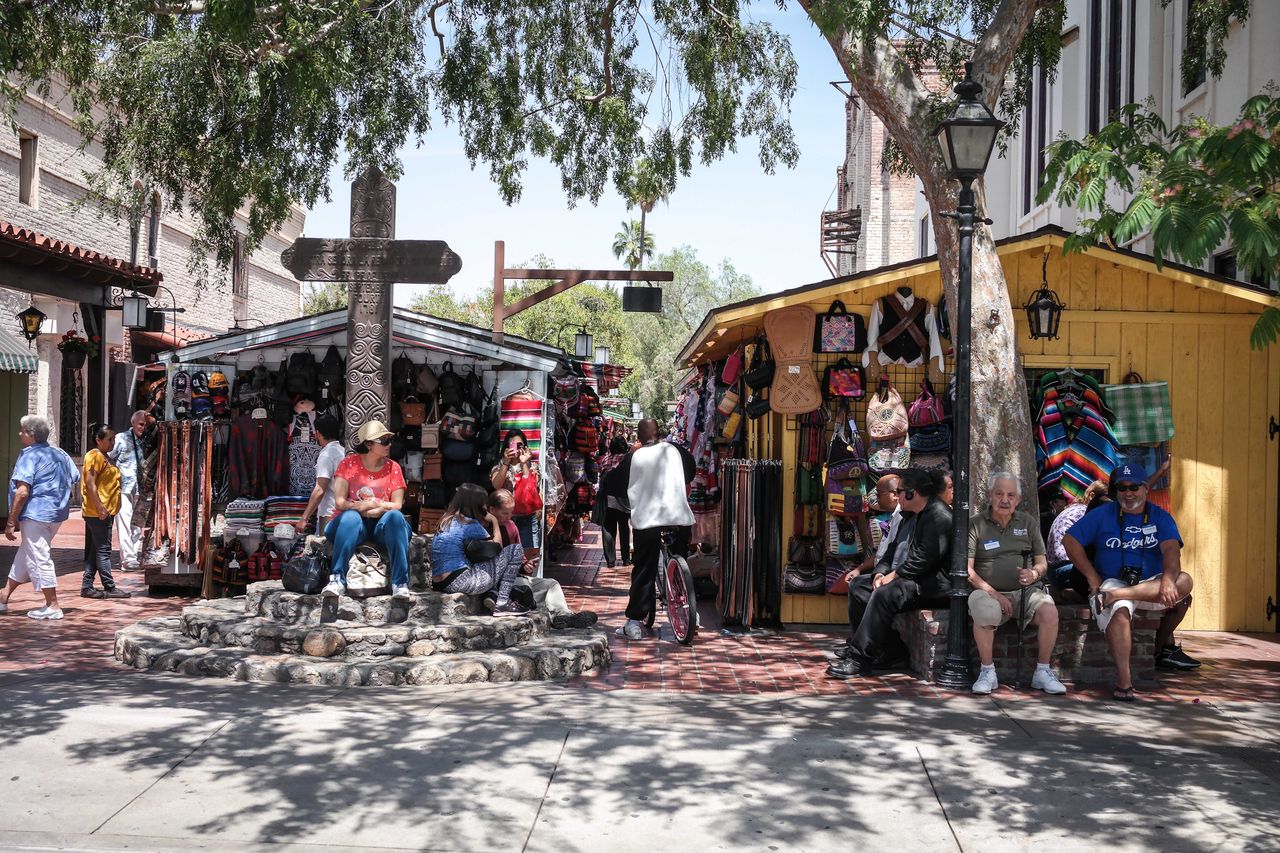 Visitors beside colorful market stalls and a stone fountain on Olvera Street in 2014