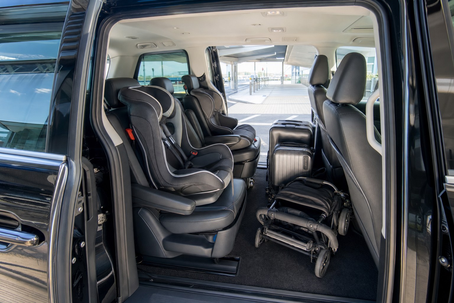 Clean minivan interior with child seats, luggage room and an open airport-door view