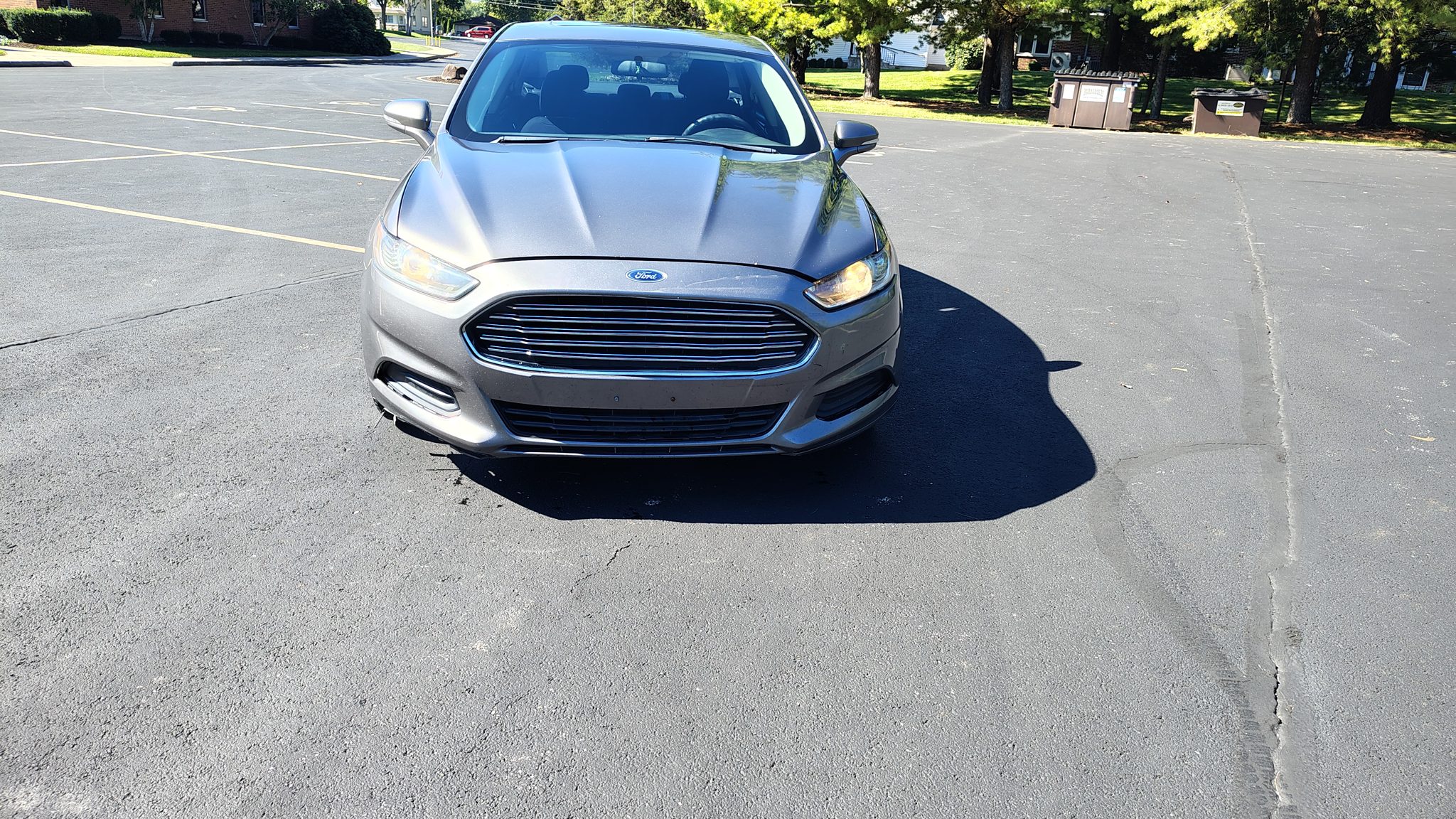 Front view of a silver Ford sedan in the dealership parking lot