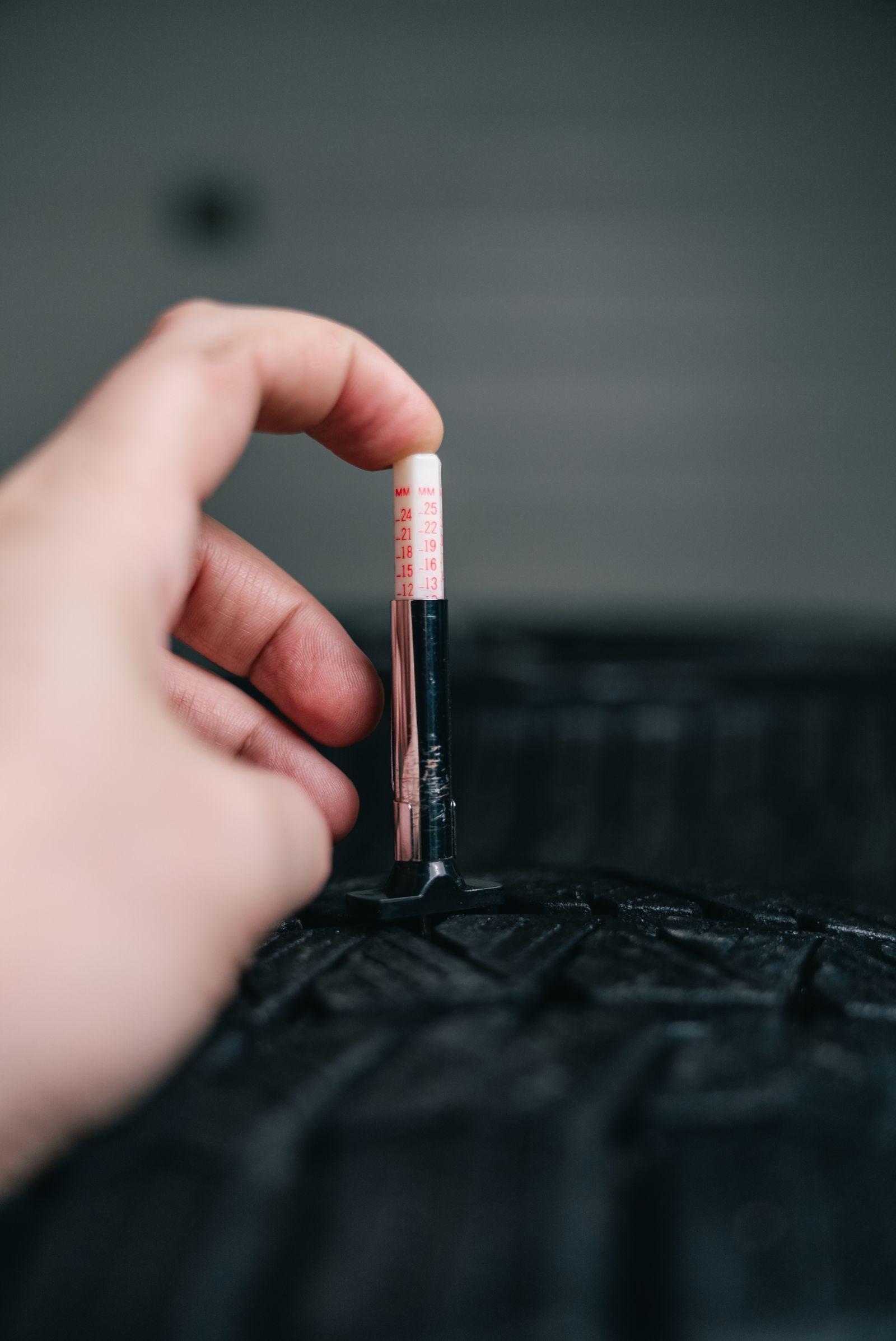 Buyer checking used car tire tread with a depth gauge