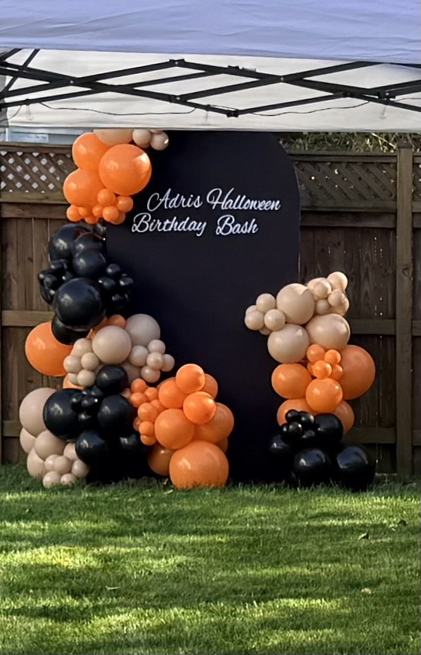 Halloween balloon display with an orange, black, and cream garland from Divine Party Rentals