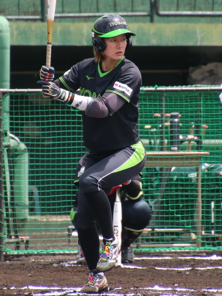 Softball player ready to hit beside a dugout fence