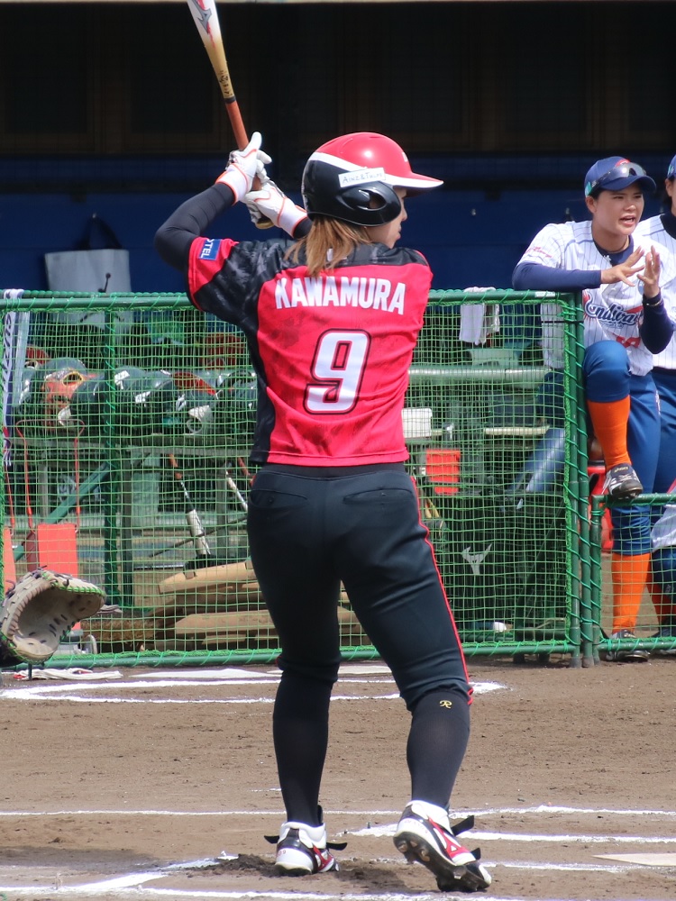 Softball batter with a teammate encouraging her from the dugout