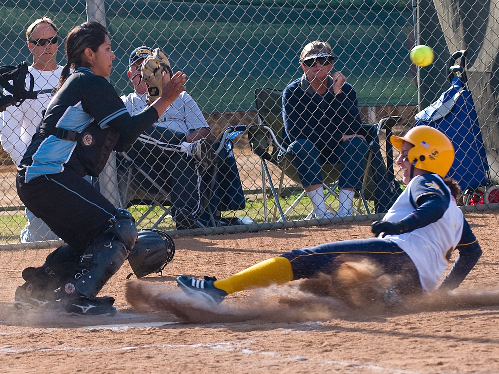 Softball catcher preparing for a play with teammates and coaches nearby
