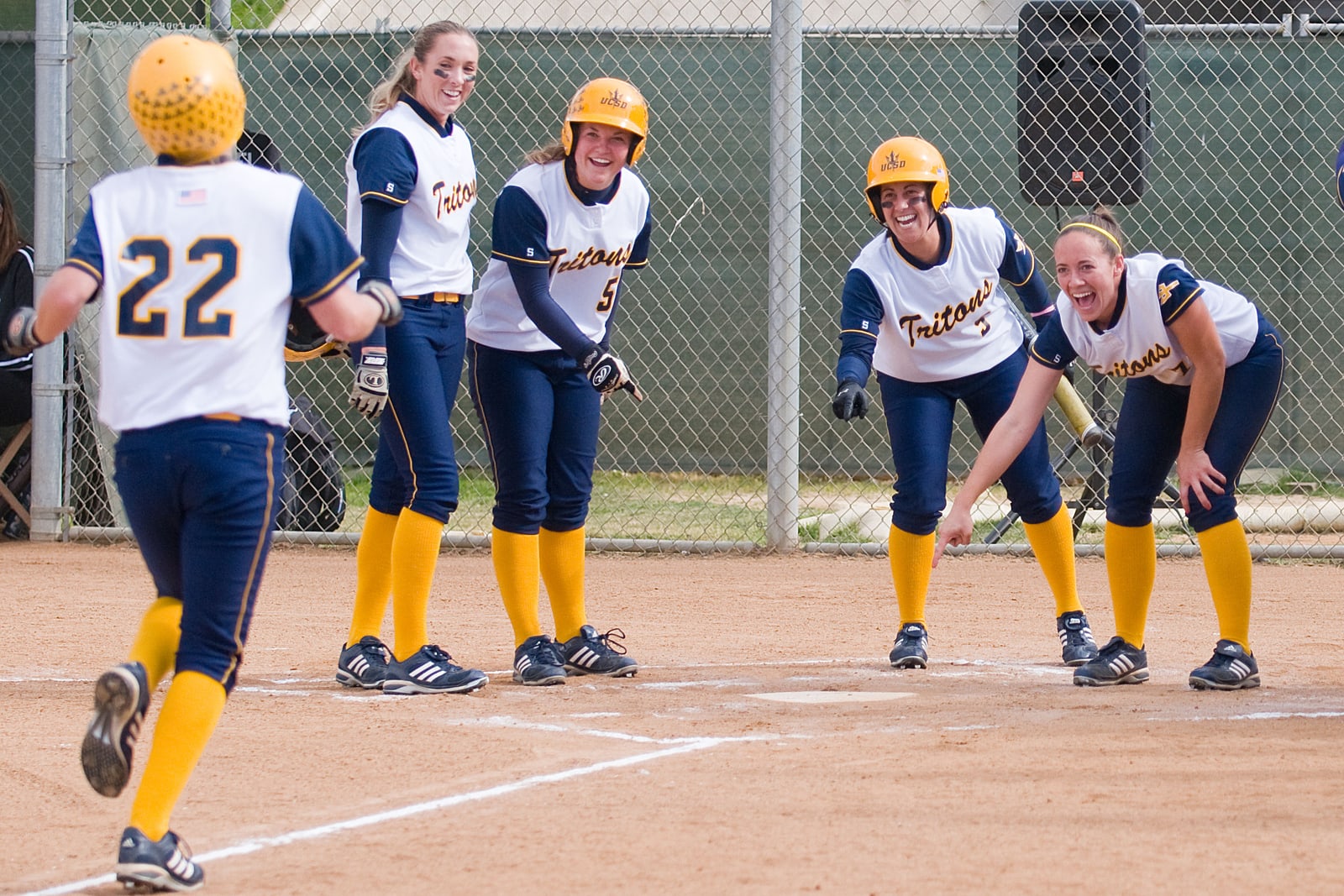 Softball players celebrating together beside the dugout