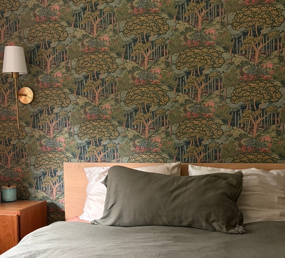 Finished bedroom with forest wallpaper behind the bed