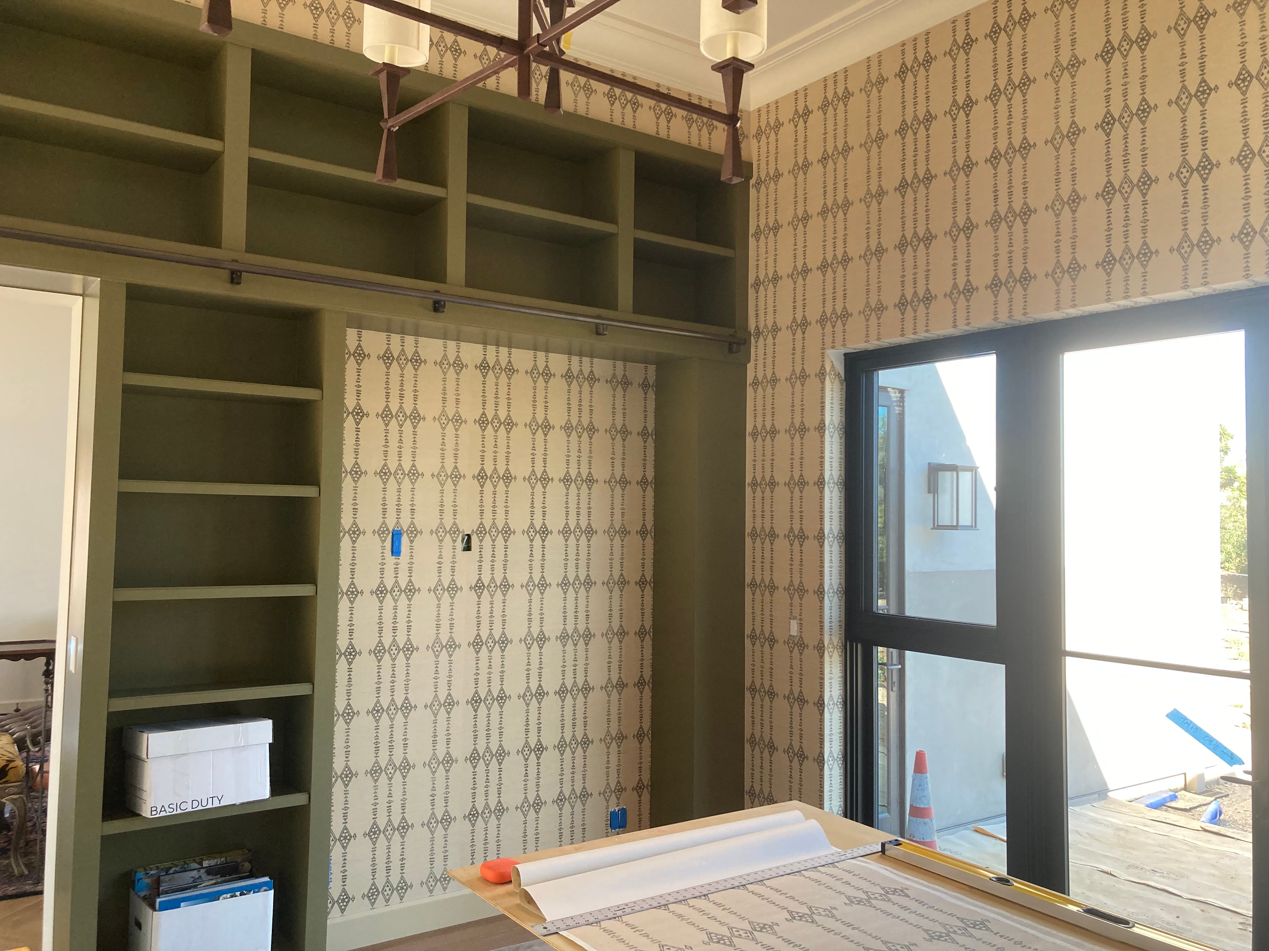 Wallpaper installation in progress beside custom shelving