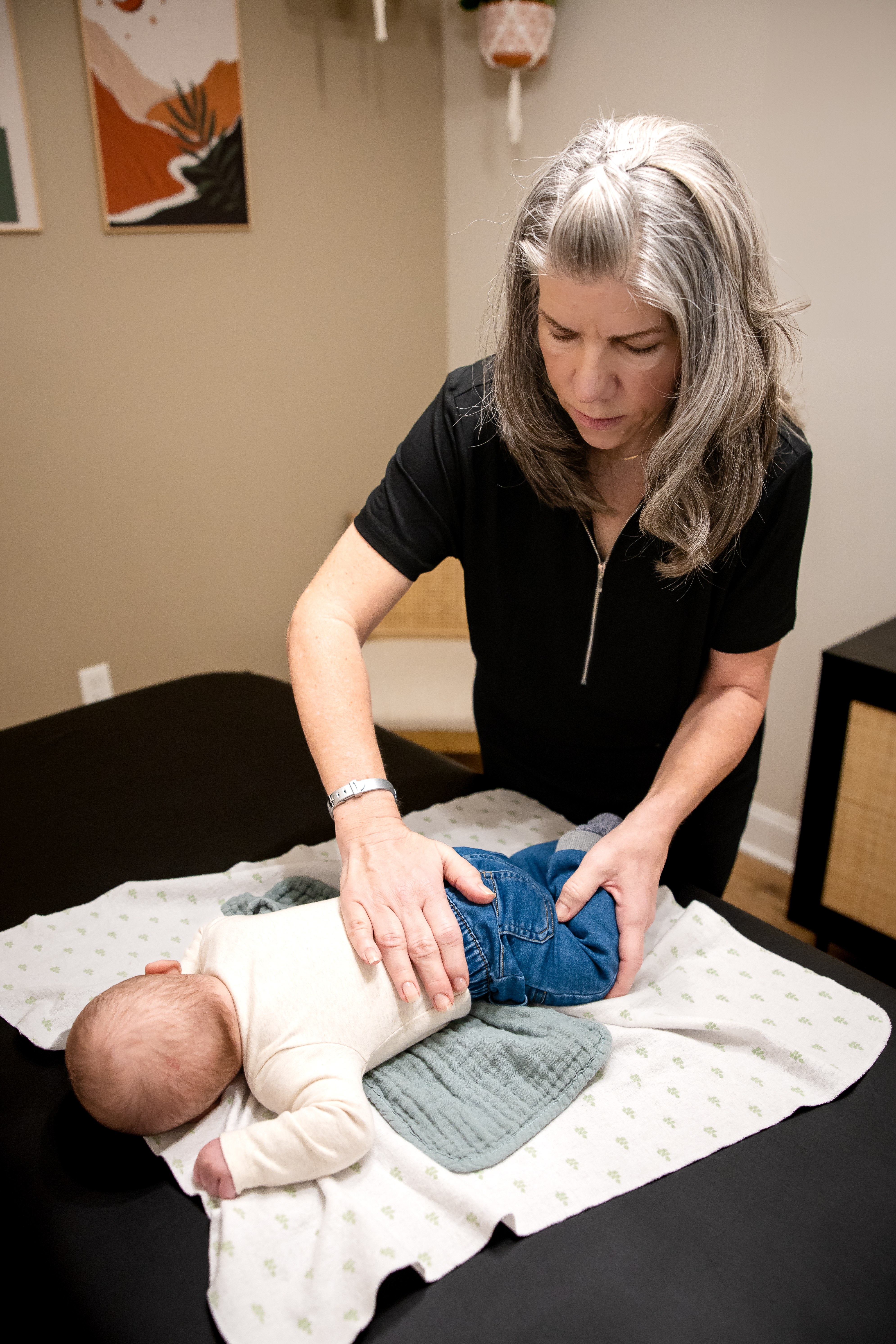 Gentle hands supporting a baby during a craniosacral therapy session