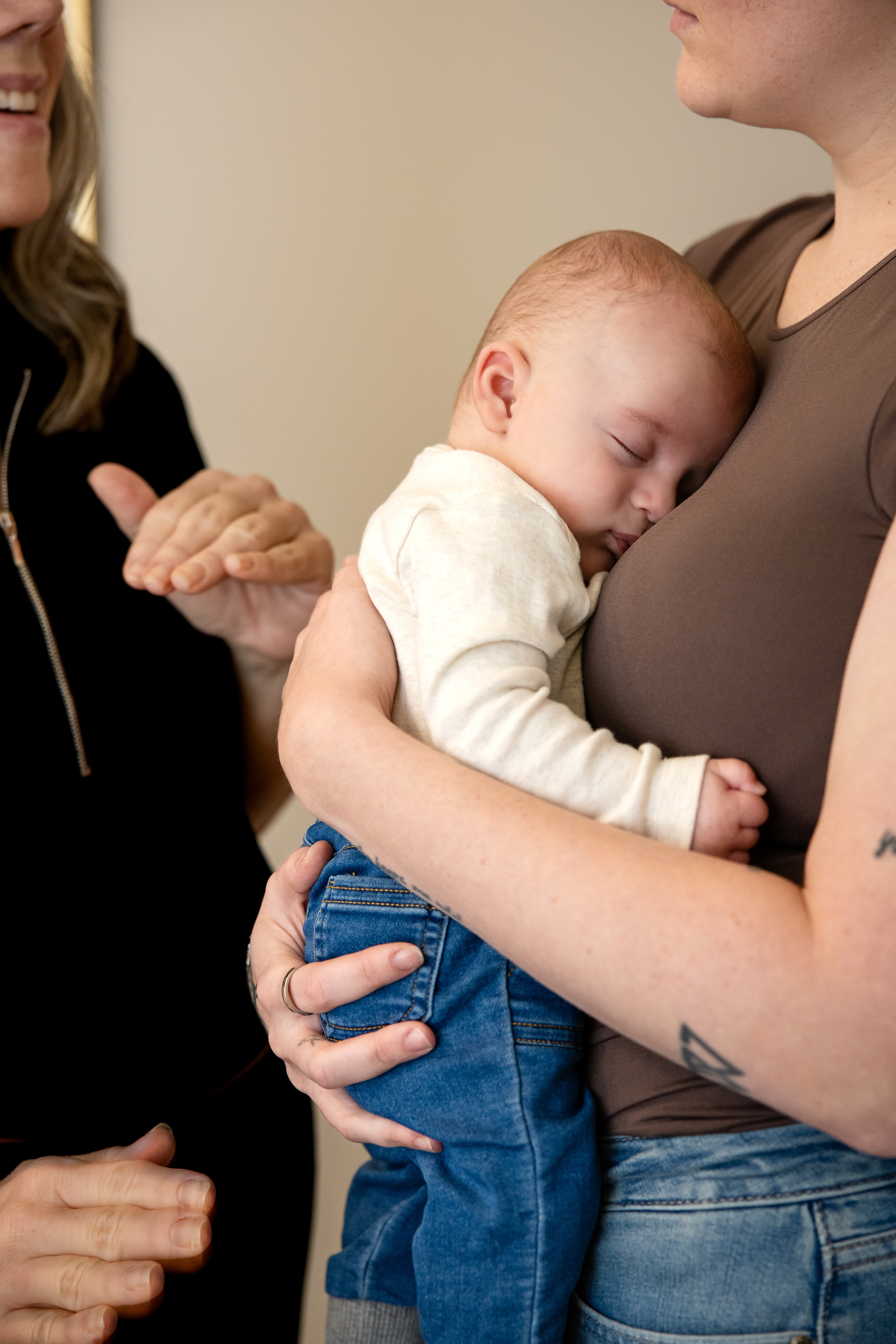 A sleeping baby held close by a parent