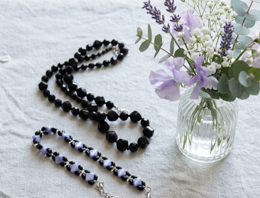 Midnight Sparkle black faceted-bead necklace styled beside a vase of lavender flowers