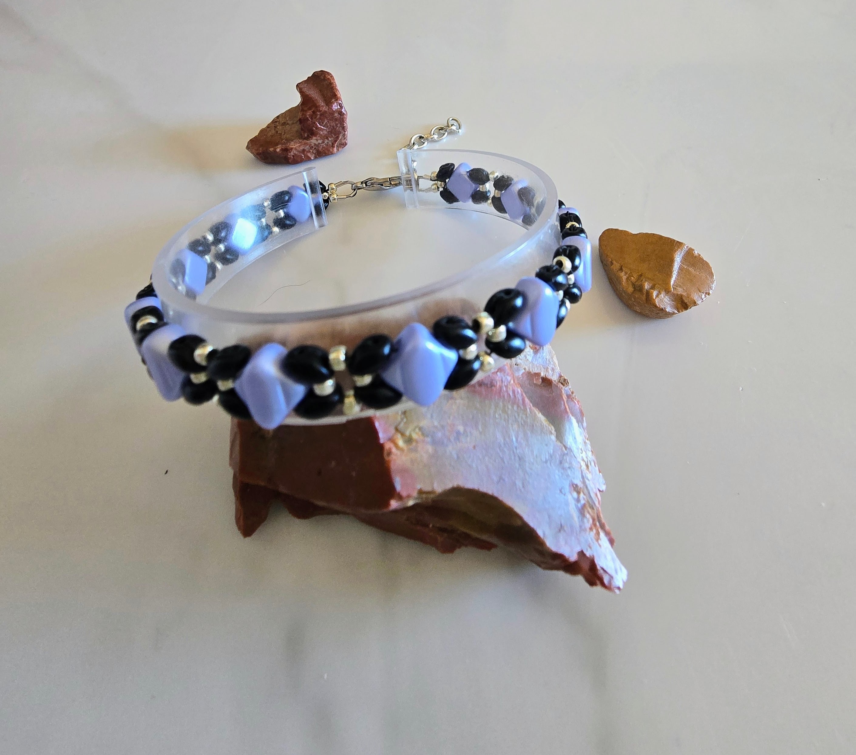 Periwinkle Silk bracelet displayed on a clear stand with natural stones